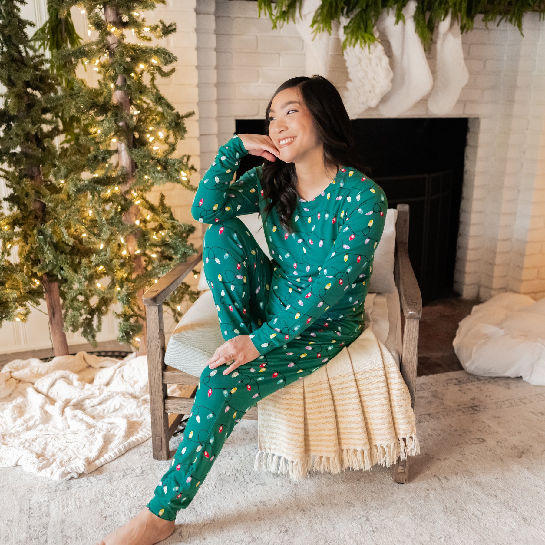 Smiling female sitting on a chair looking off to the side wearing the Women's Jogger Pajama Set in Merry and Bright