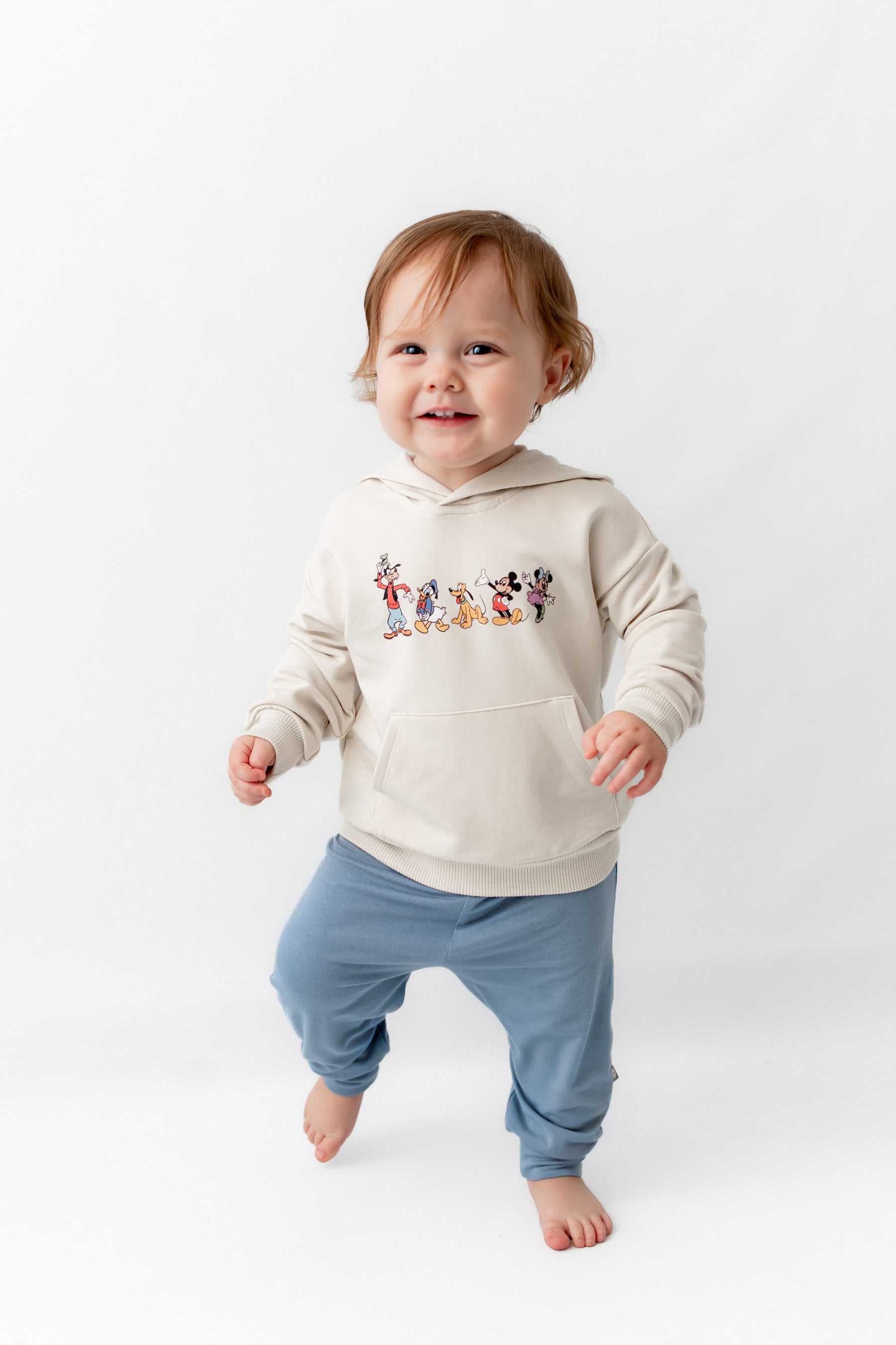Toddler  wearing mickey mouse  friends hoodie with blue pants.