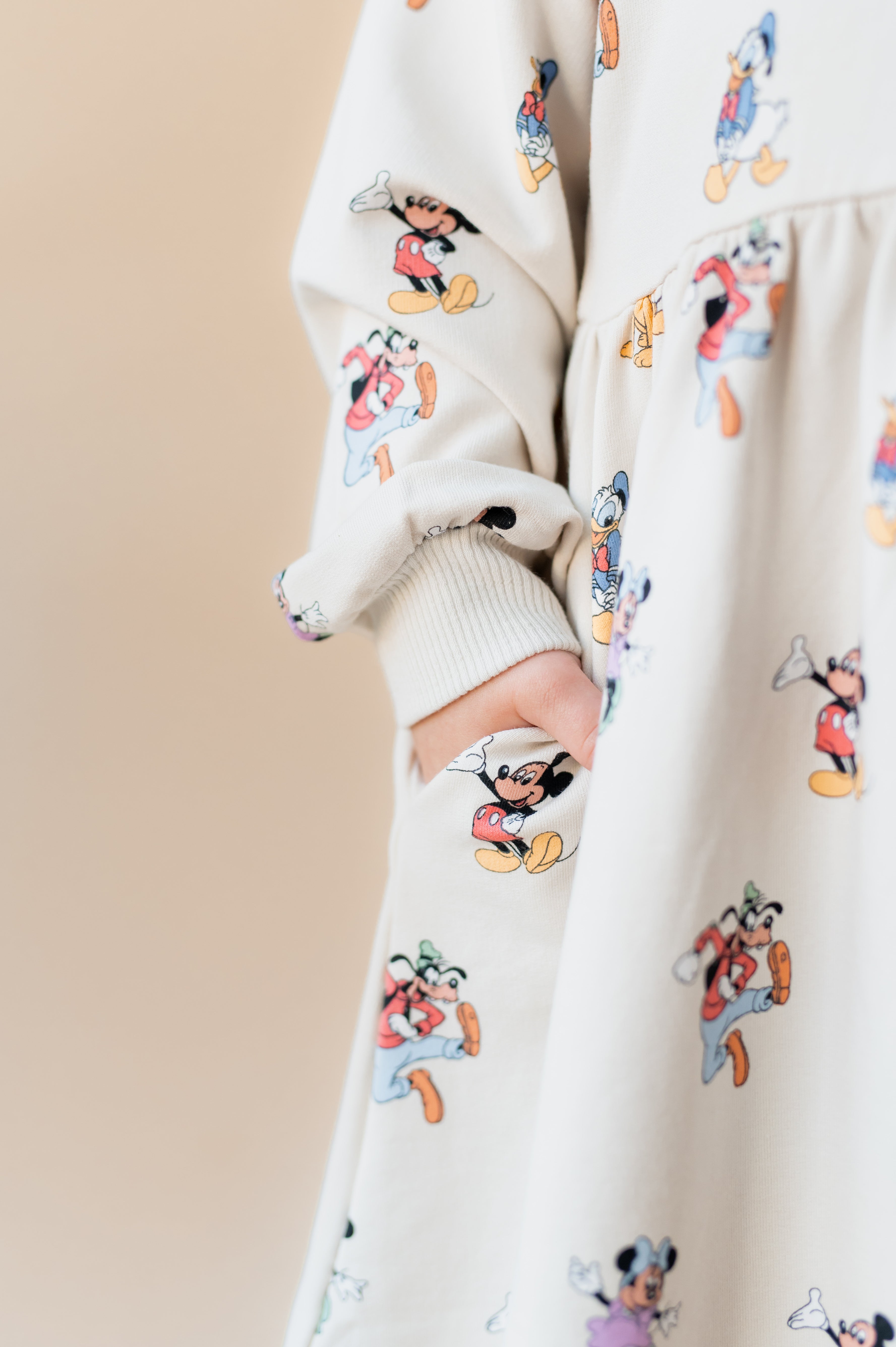 Girls hand in her pocket wearing mickey mouse & friends dress.