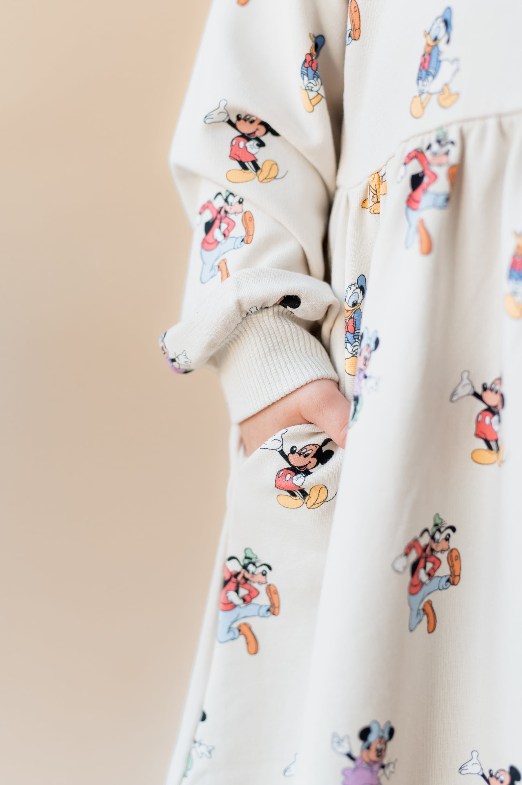 Girls hand in her pocket wearing mickey mouse & friends dress.