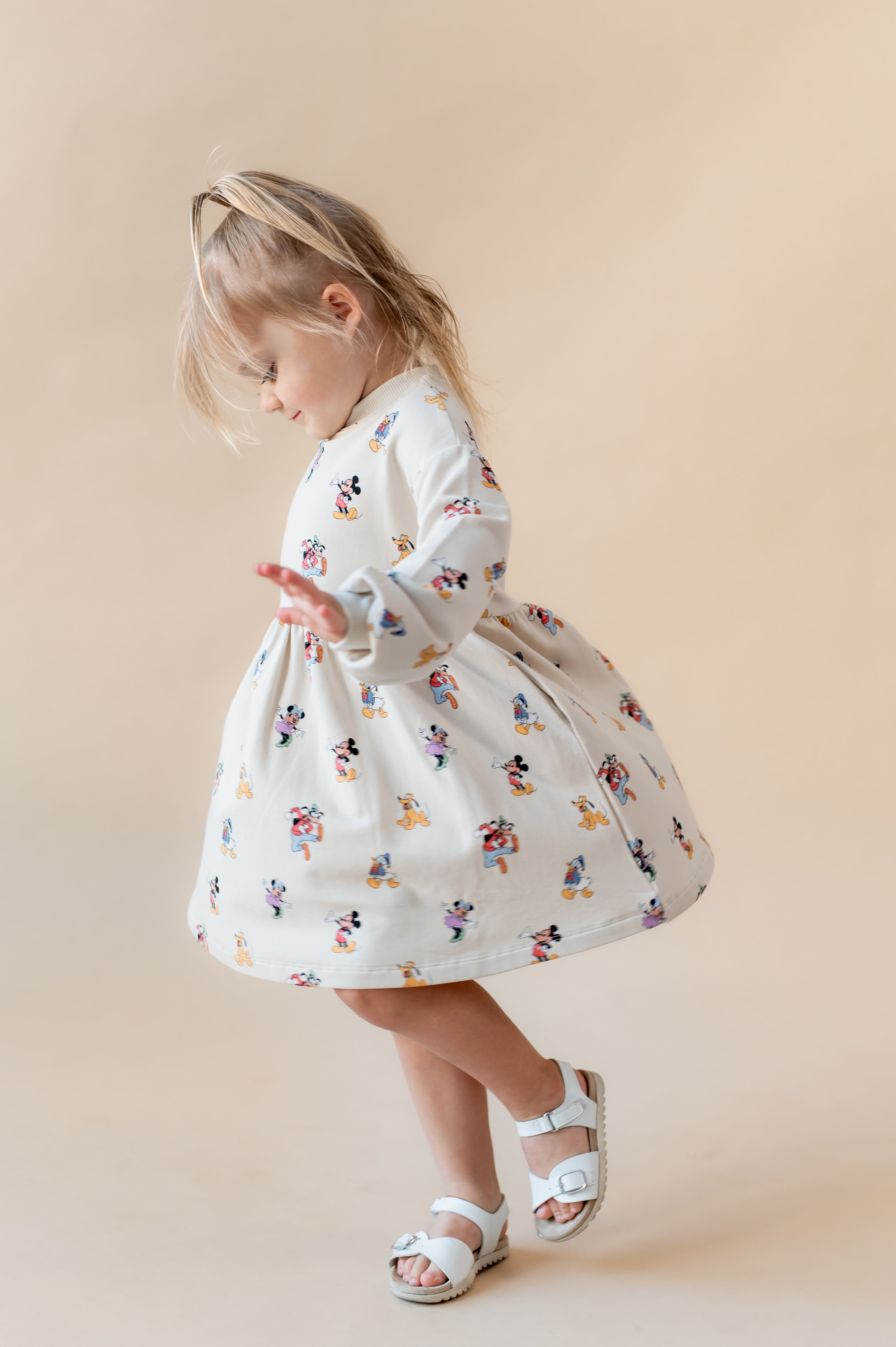 Girl twirling wearing mickey mouse & friends dress.