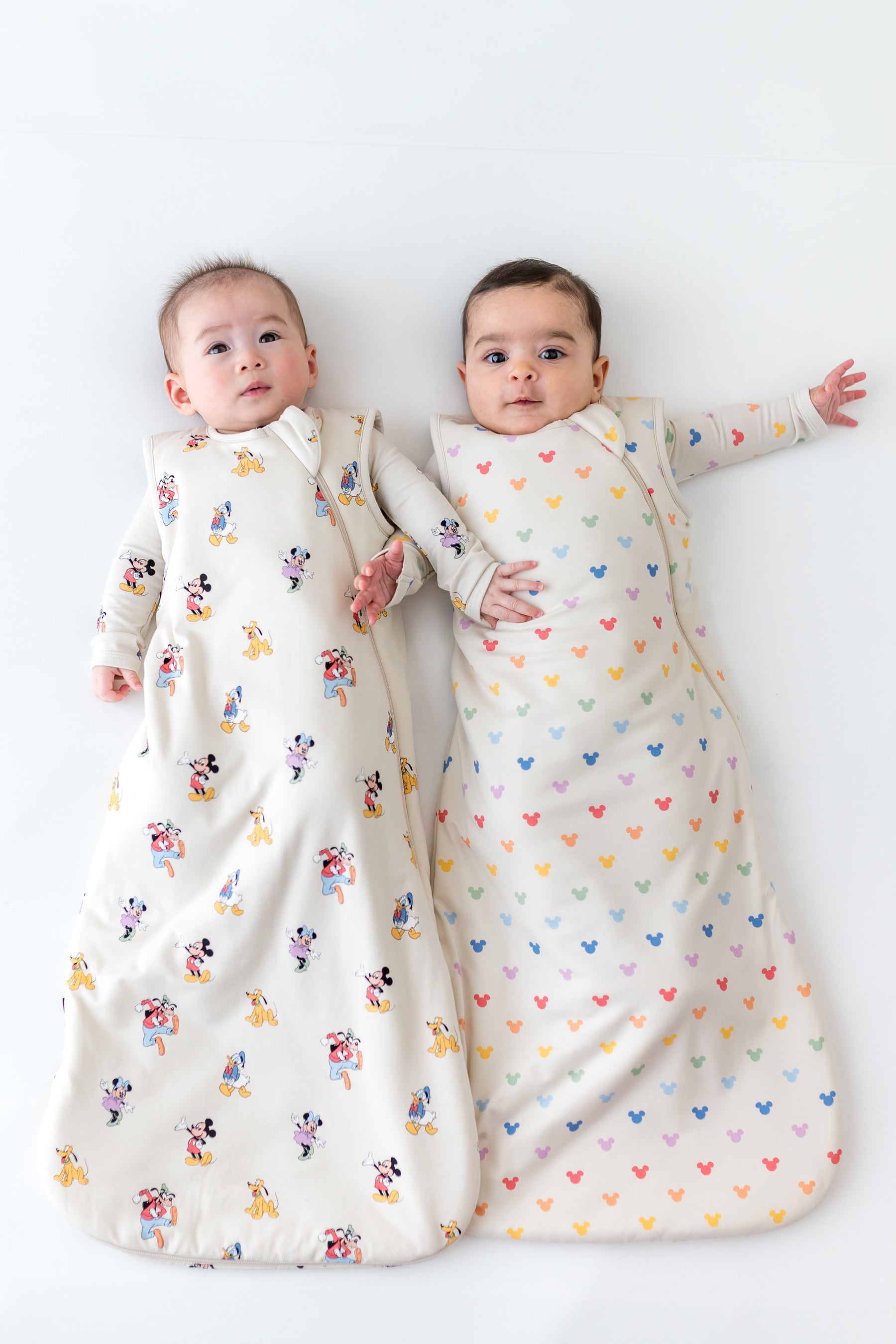 2 babies wearing sleep sacks in mickey mouse patterns