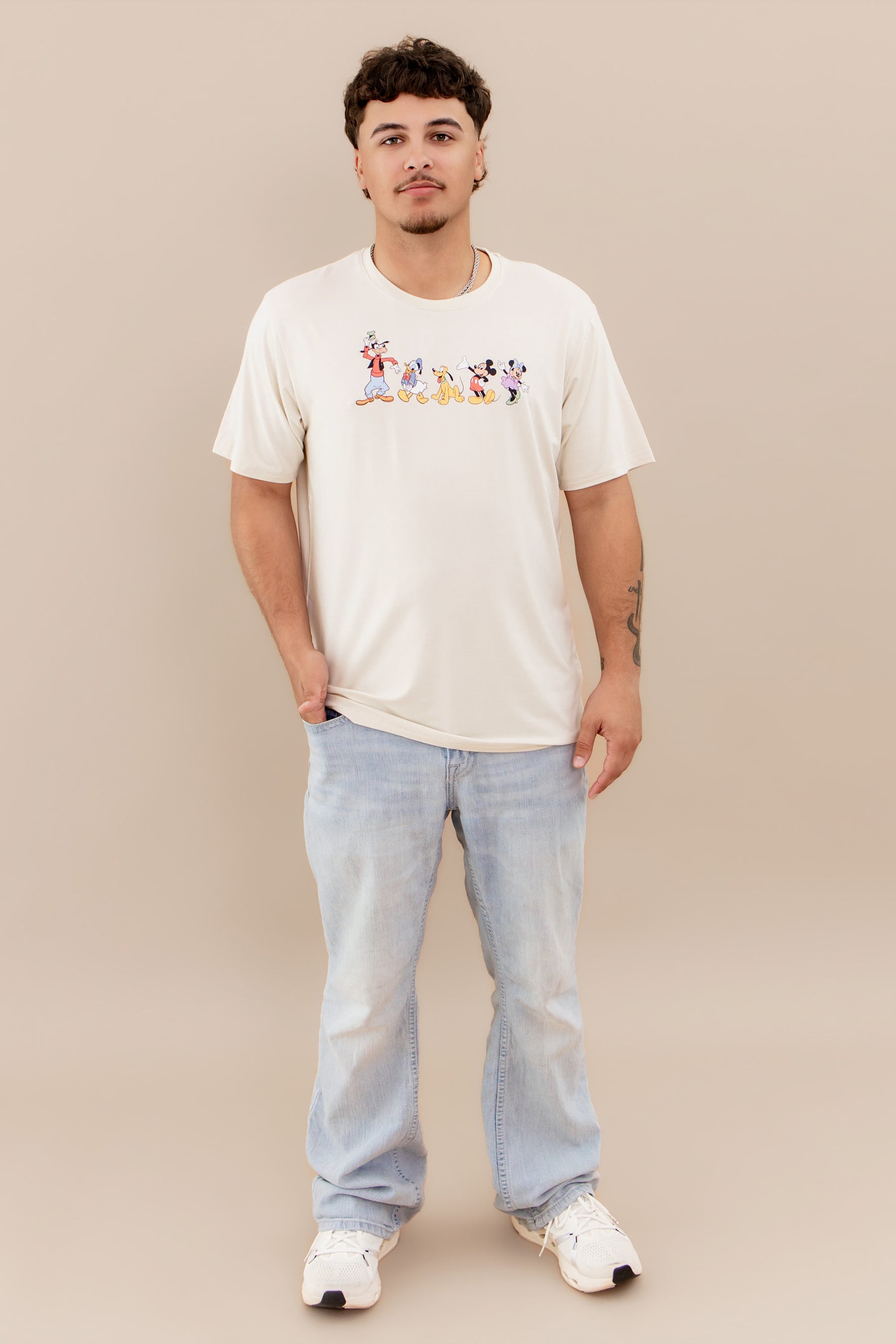 Man wearing mickey and friends graphic tee and light colored jeans and sneakers