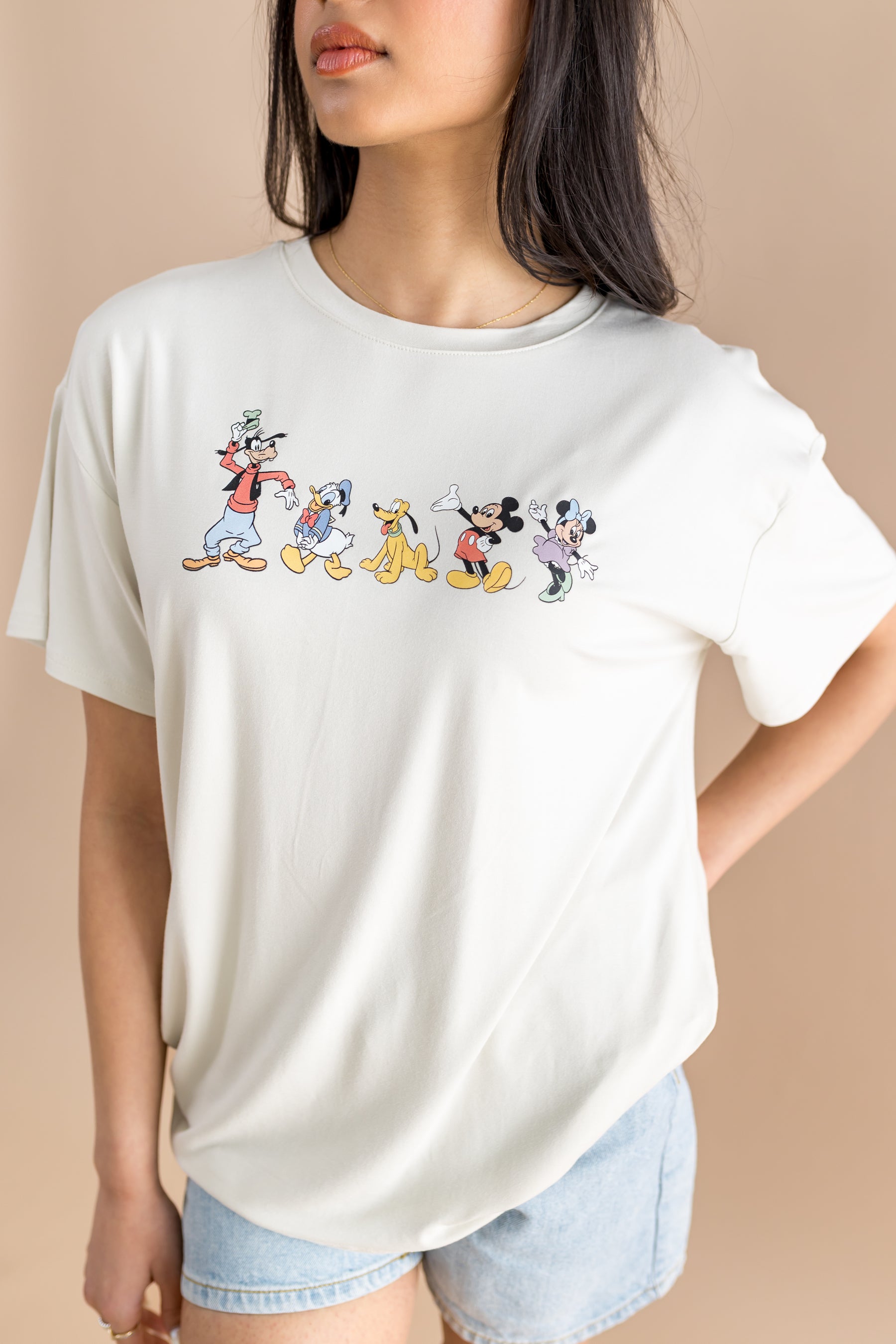 Woman wearing jean shorts and graphic tee with mickey and friends 