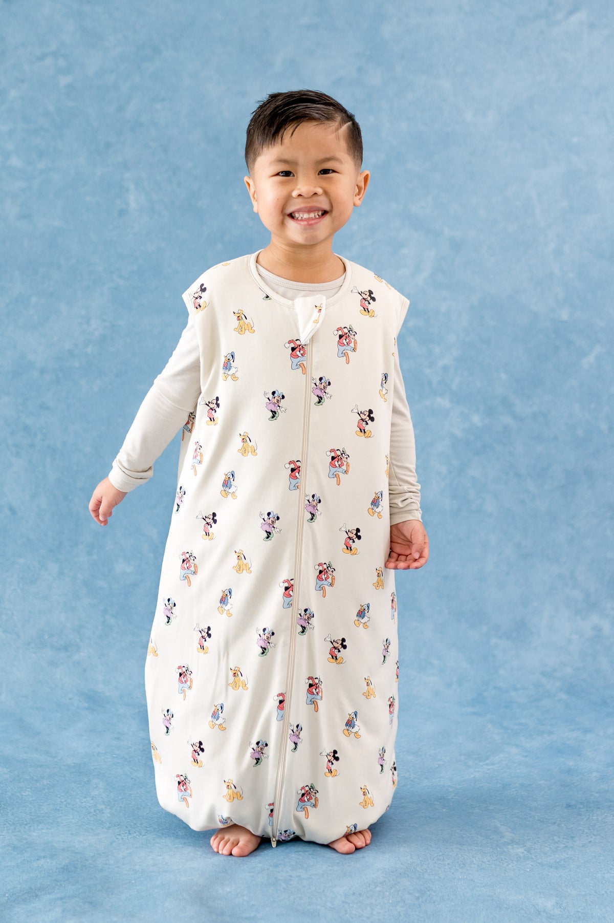 Young boy wearing a sleep bag walker with a mickey and friends pattern