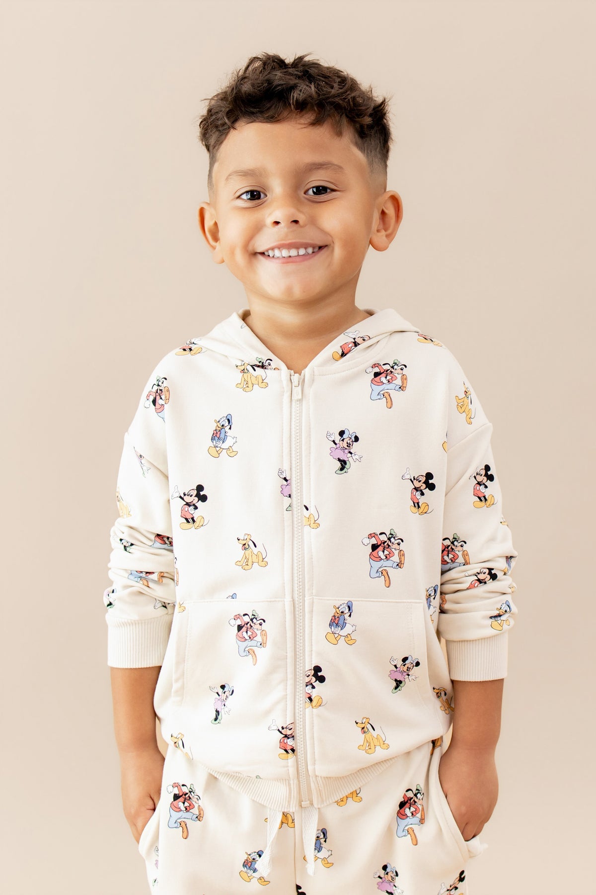 Child wearing a zip up hoodie with mickey and friend pattern