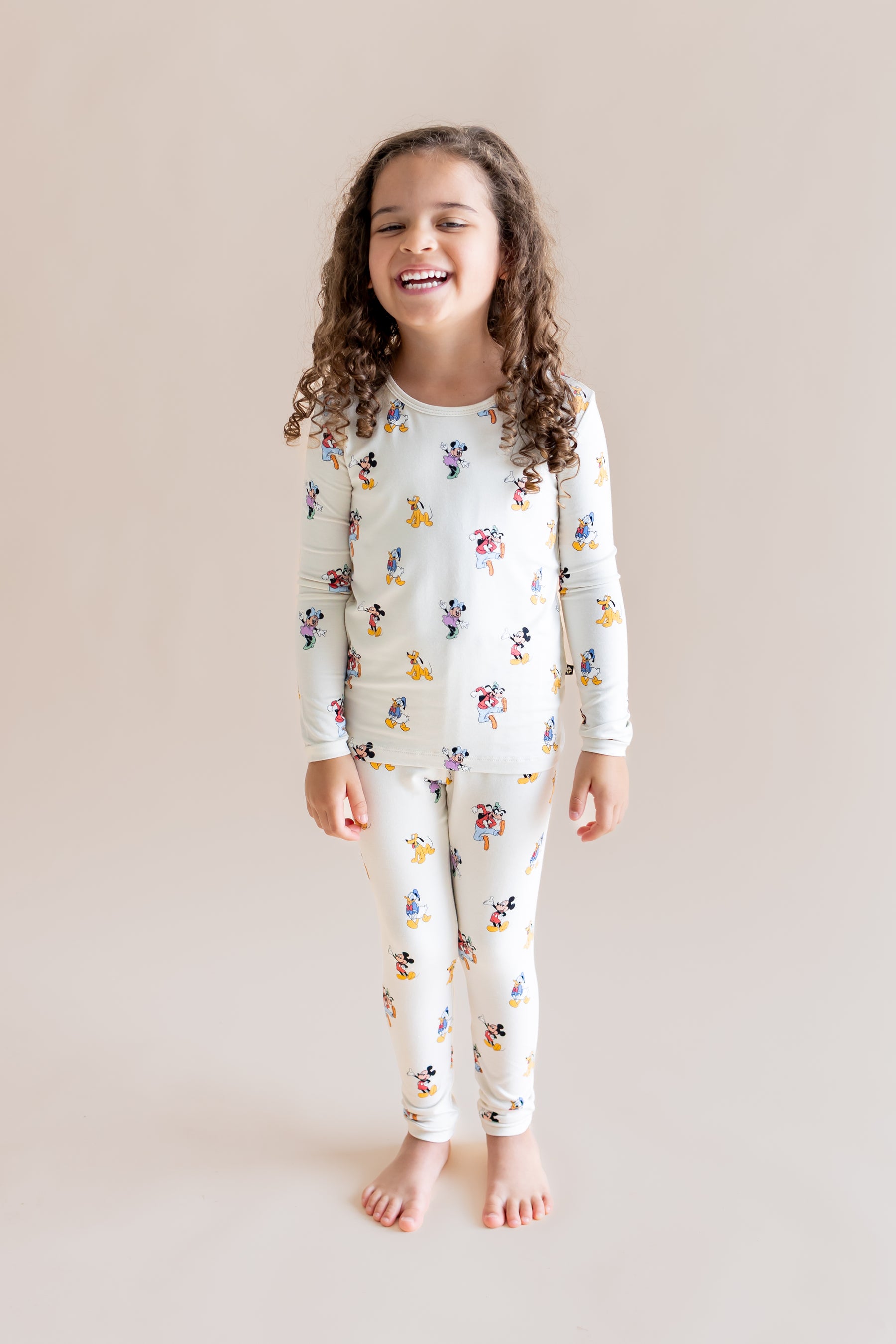 Girl wearing Long Sleeve Pajamas in Mickey Mouse & Friends print on a cream background