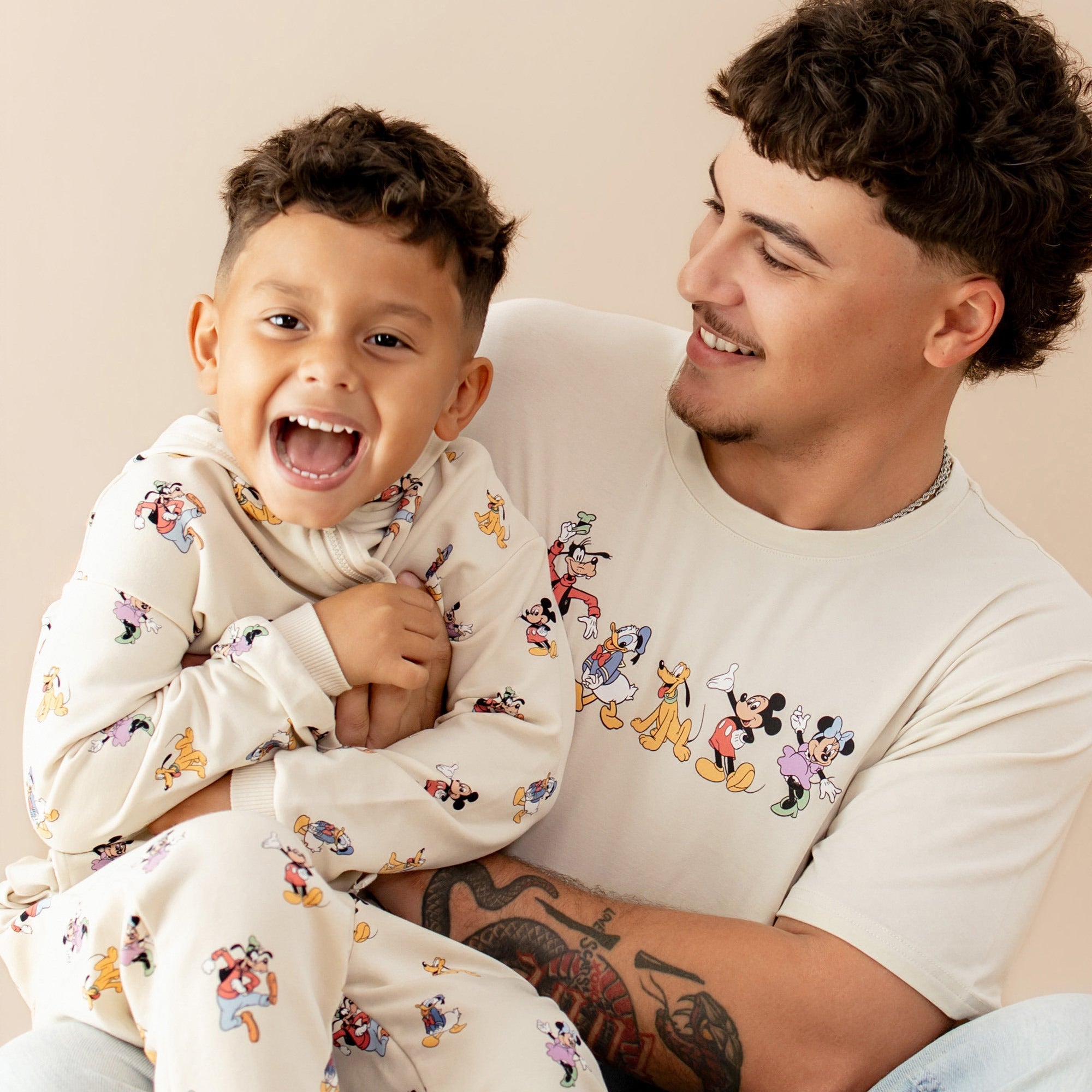 Dad and toddler wearing matching Mickey and Friends print apparel