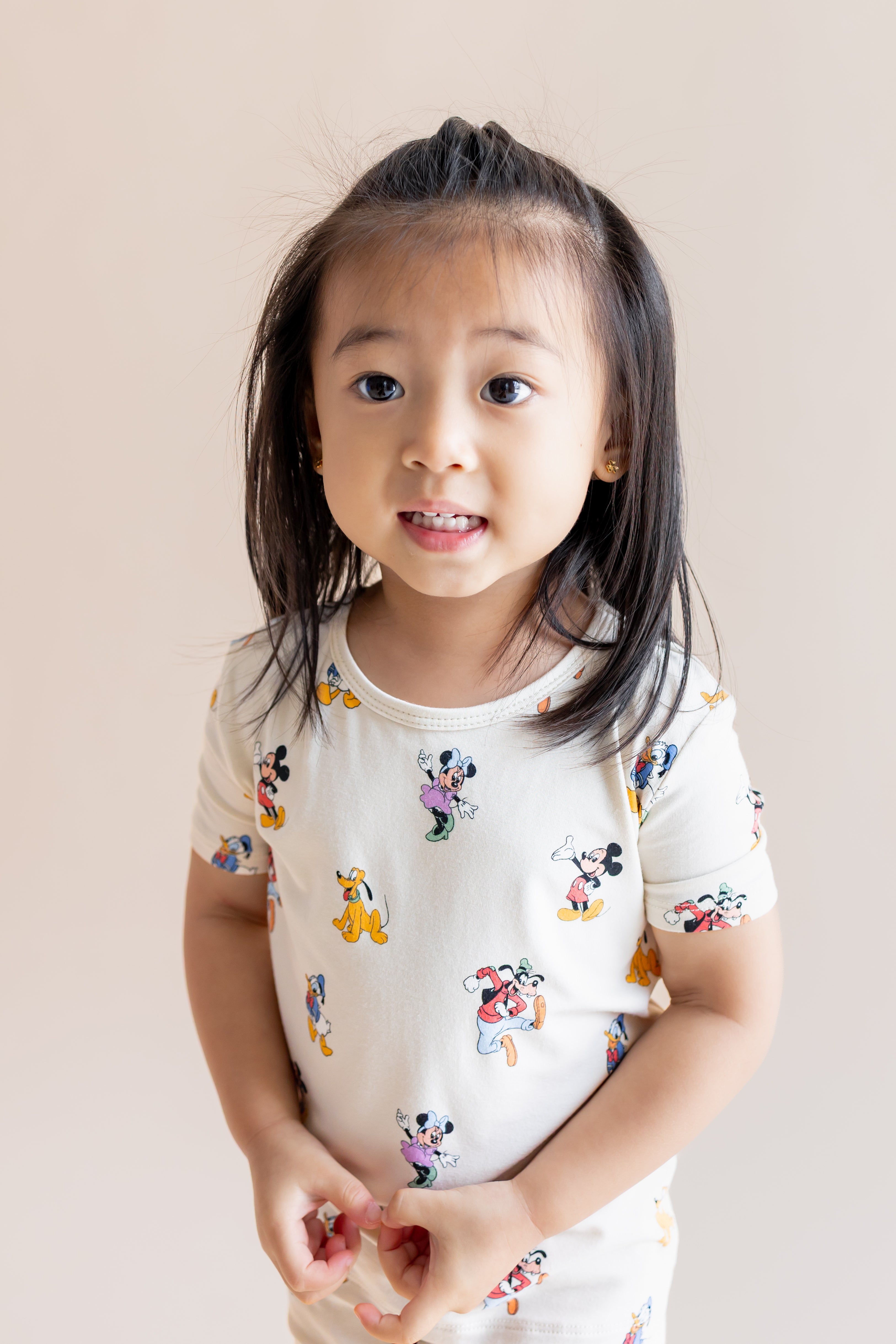 Girl wearing Short Sleeve Pajamas in Mickey Mouse & Friends print on a cream background