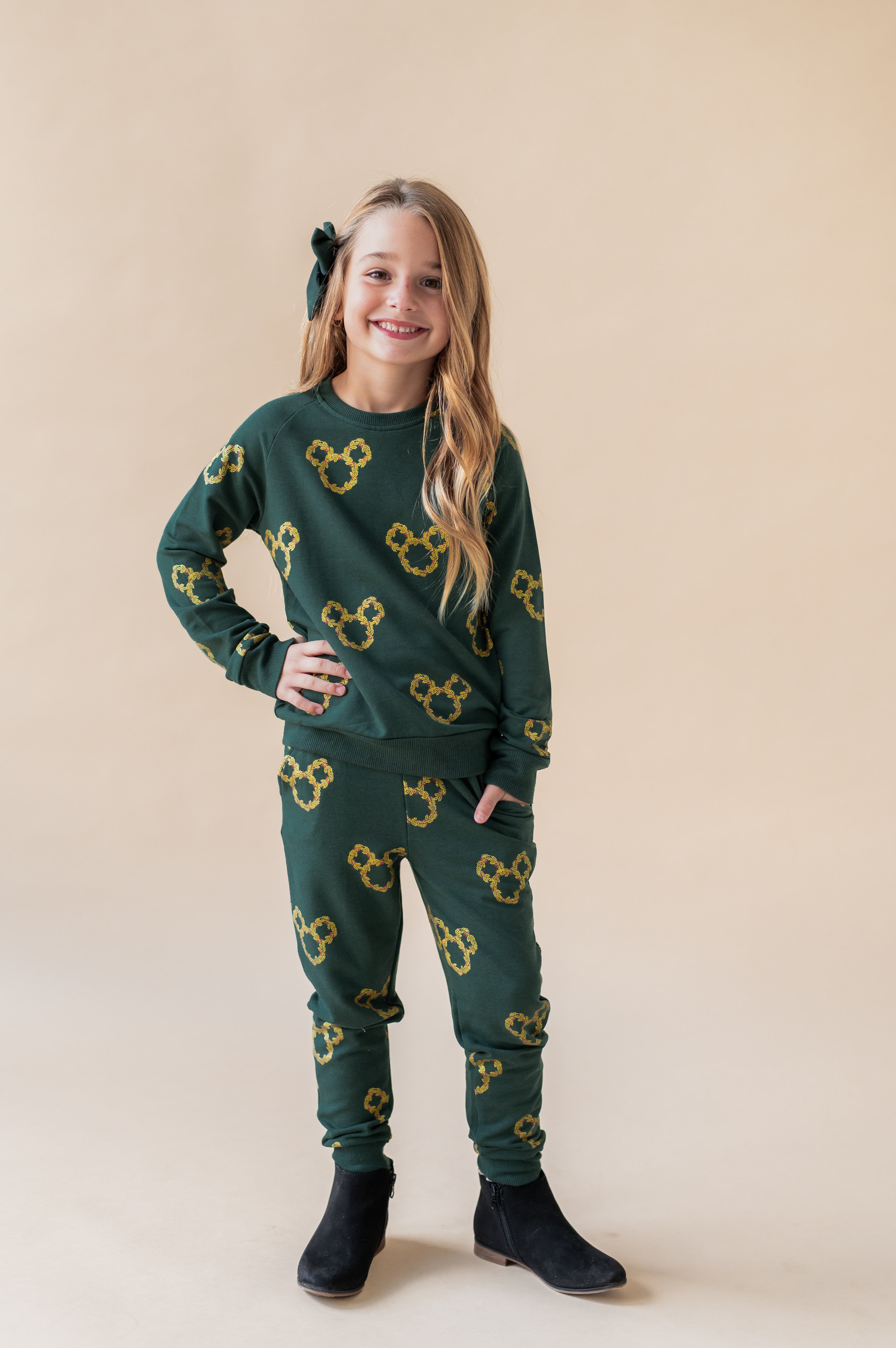 Girl wearing Long Sleeve Jogger Set in Mickey Christmas Wreath print on a beige background