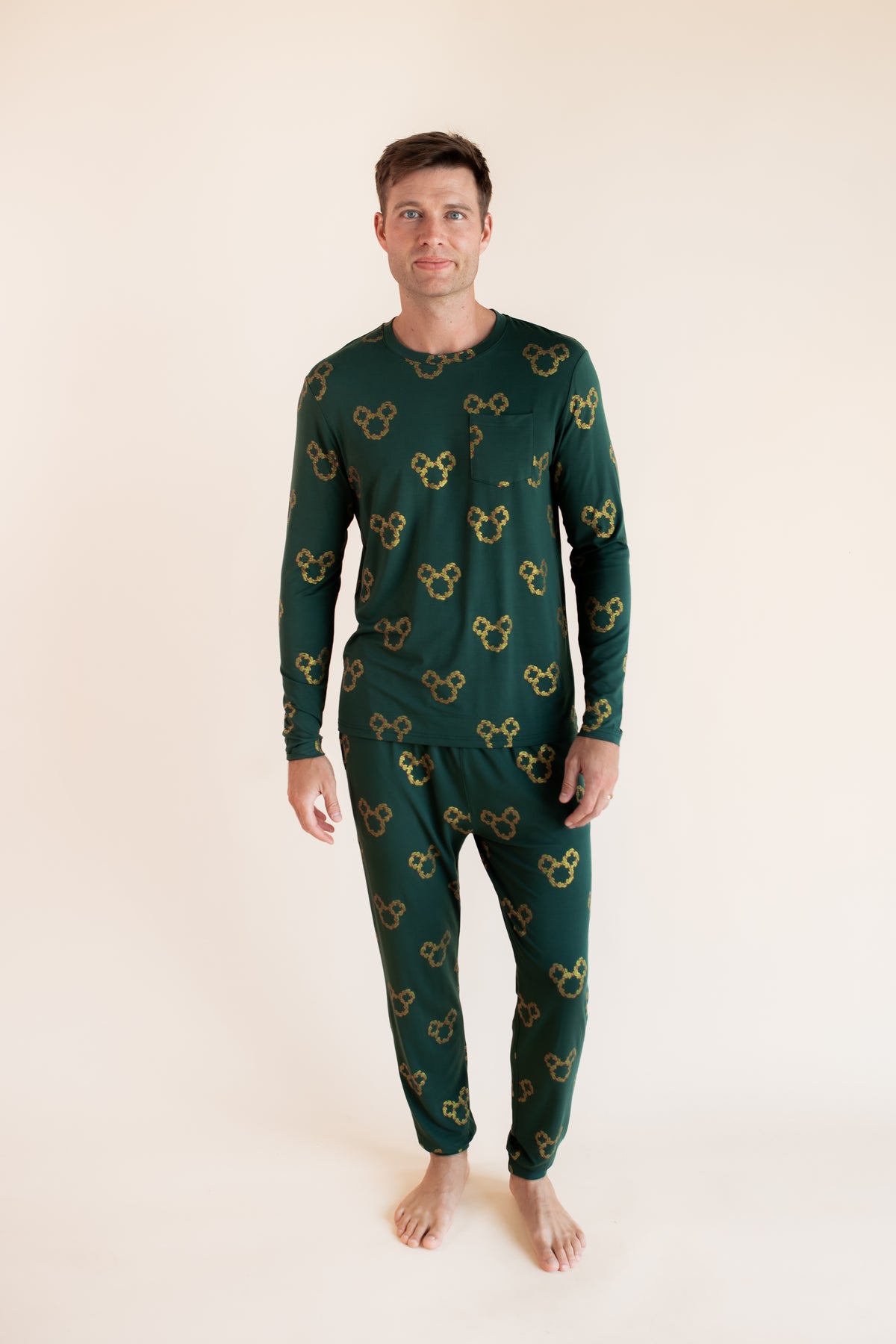 Modal wearing Men's Jogger Set in Mickey Christmas Wreath print on a beige background