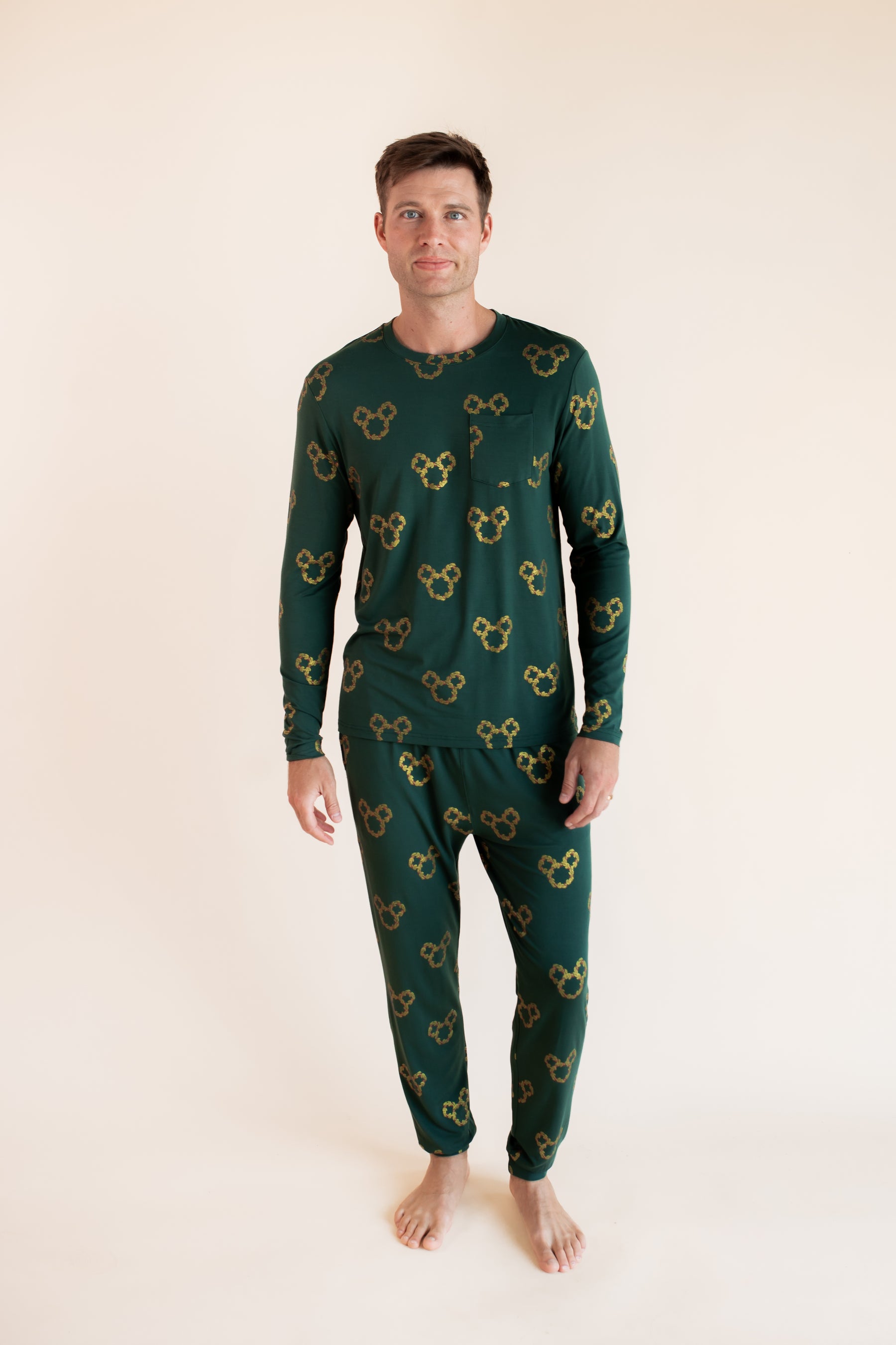 Modal wearing Men's Jogger Set in Mickey Christmas Wreath print on a beige background