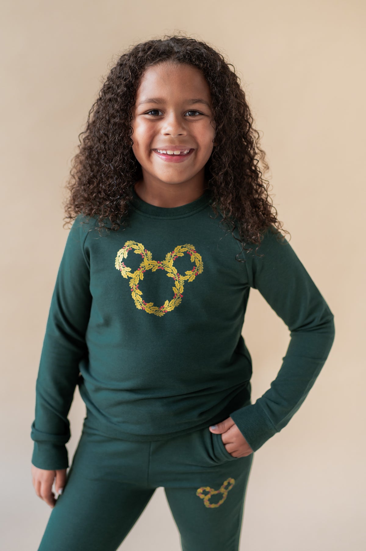 Girl wearing Long Sleeve Jogger Set in Mickey Christmas Wreath print in the center in Cypress color on a beige background