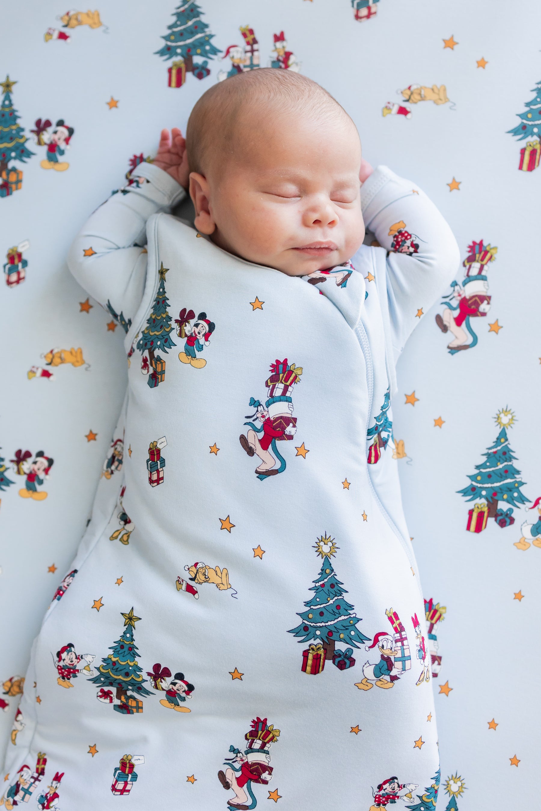 Baby sleeping in Sleep Bag in Mickey & Friends Christmas 1.0 print lying on similar print crib sheet