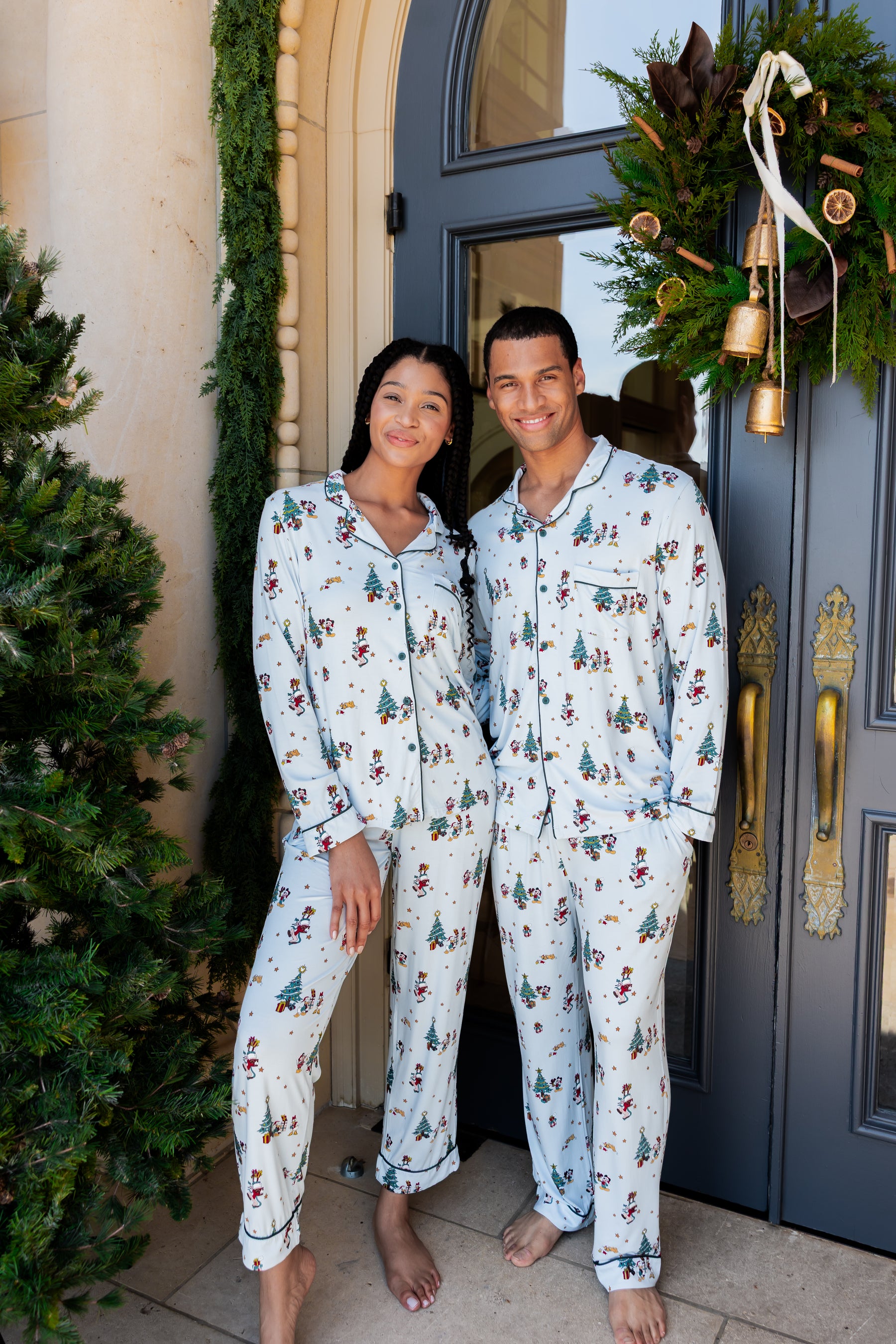 Man and woman wearing Long-Sleeved Pajama Set in Mickey & Friends Christmas print standing outdoors