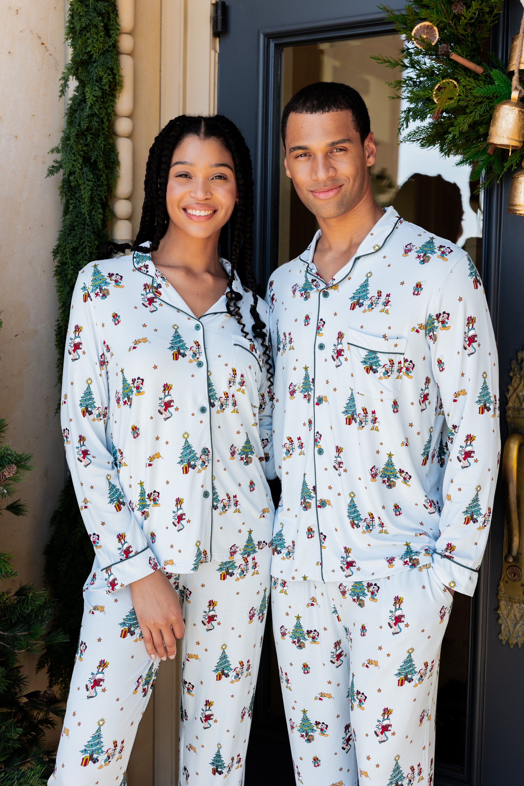 Man and woman wearing Long-Sleeved Pajama Set in Mickey & Friends Christmas print standing outdoors