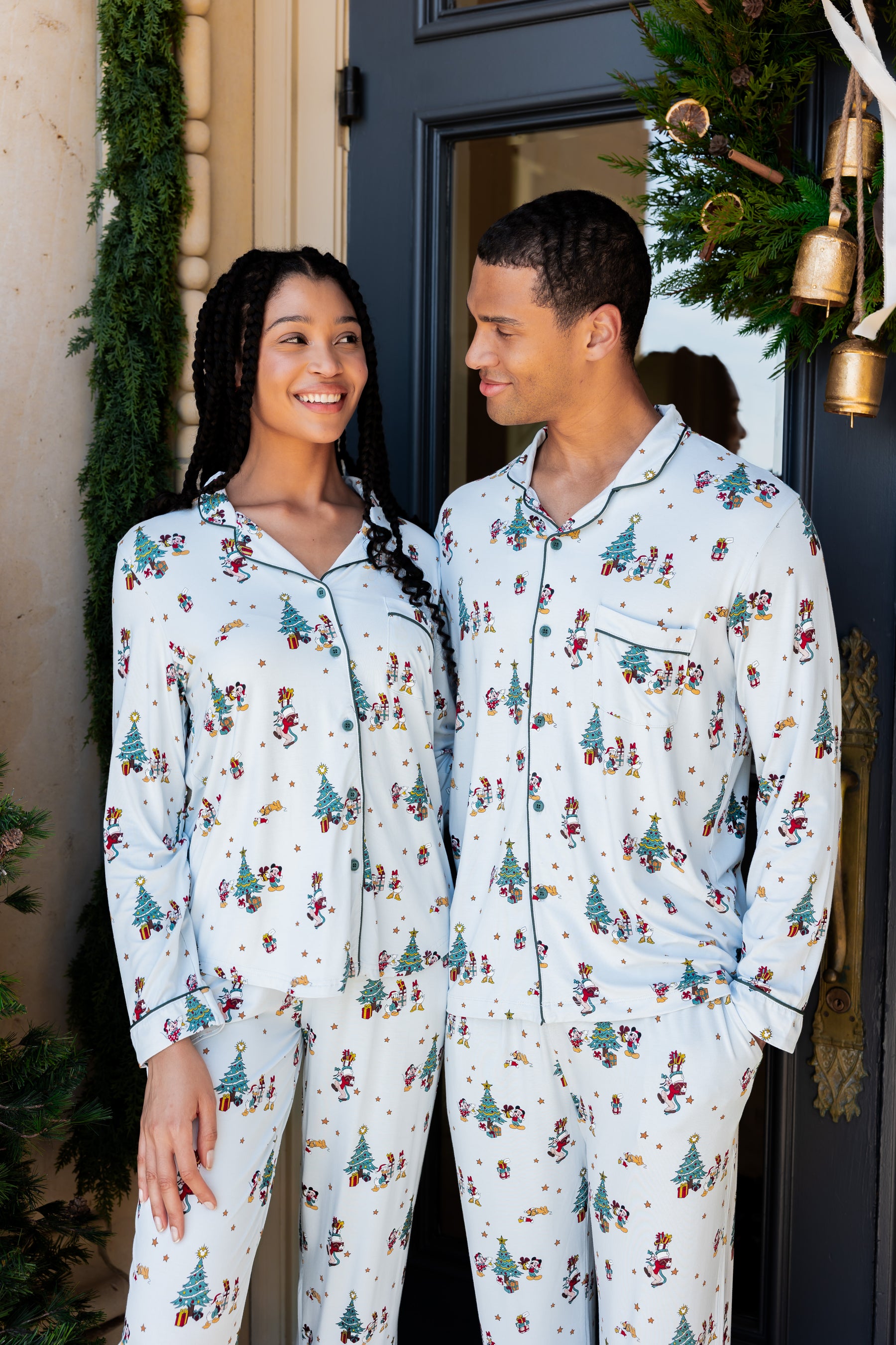 Man and woman wearing Long-Sleeved Pajama Set in Mickey & Friends Christmas print standing outdoors