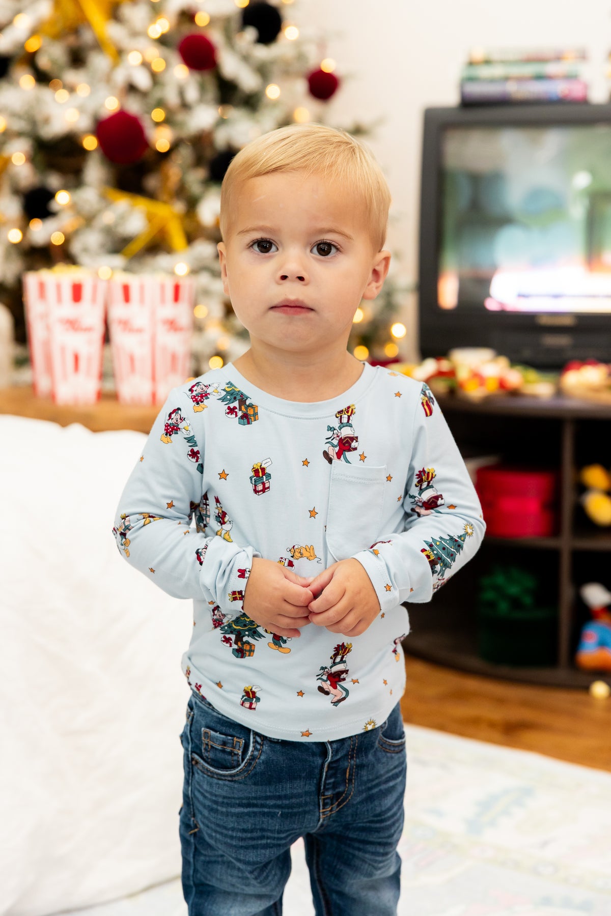 Boy wearing Long Sleeve Toddler Crew Neck Tee in Mickey & Friends Christmas print over blue jeans