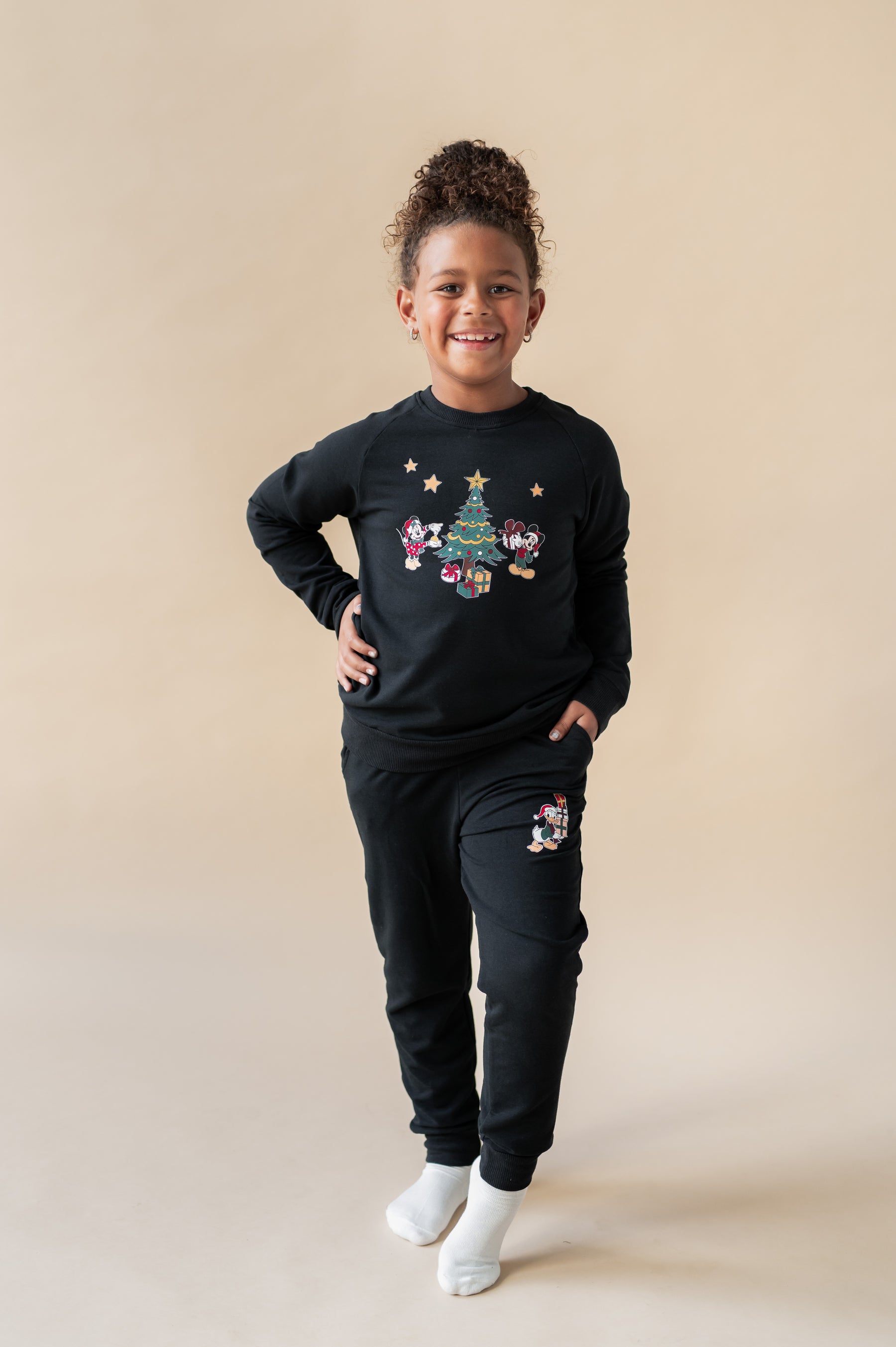 Girl wearing Long Sleeve Jogger Set in Mickey & Friends Christmas print on Midnight color on a beige background