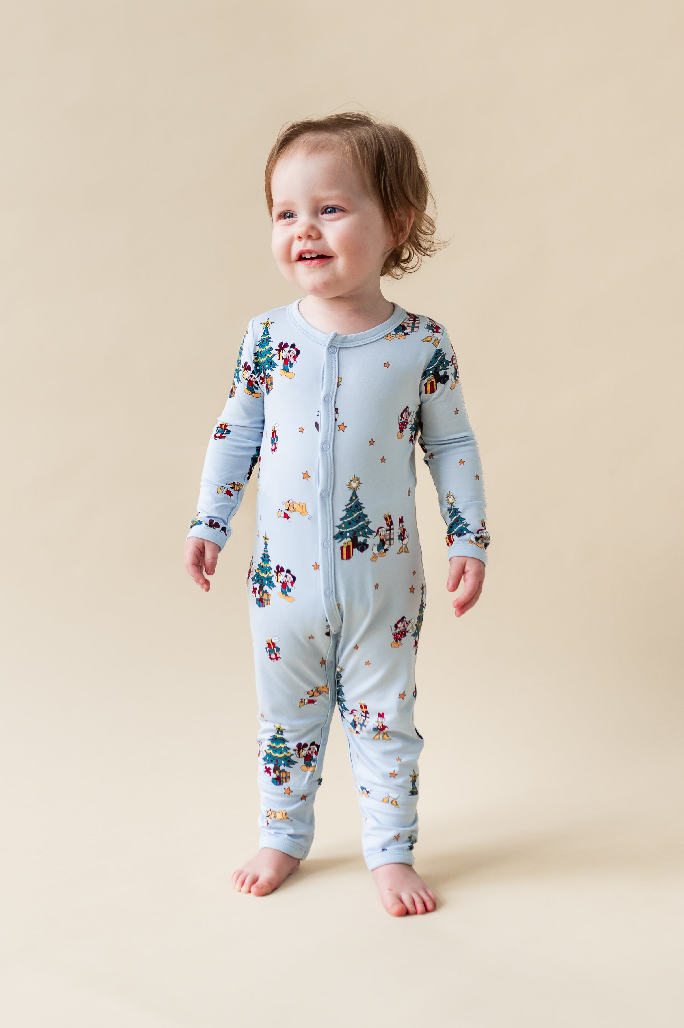 Toddler wearing Romper in Mickey & Friends Christmas print with snap buttons on a beige background