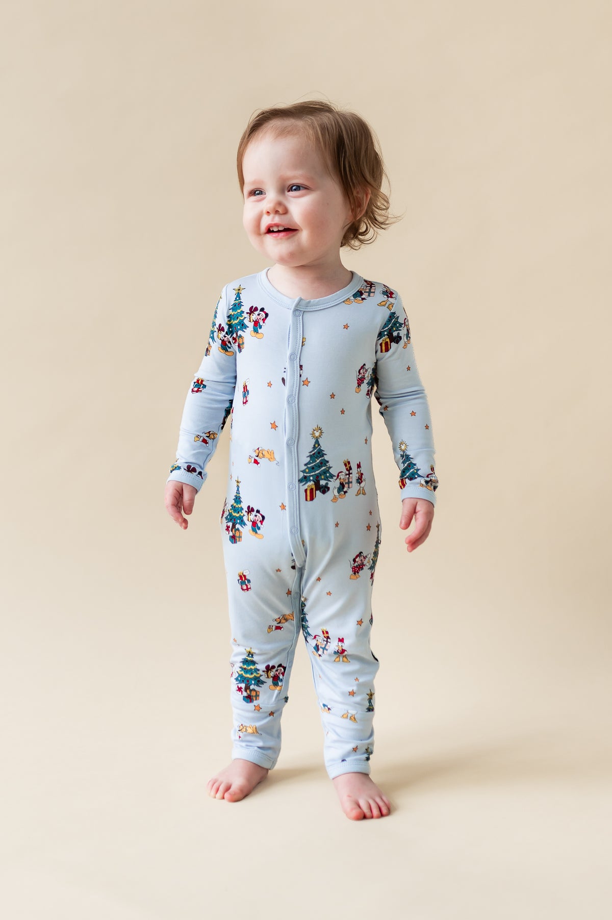 Toddler wearing Romper in Mickey & Friends Christmas print with snap buttons on a beige background