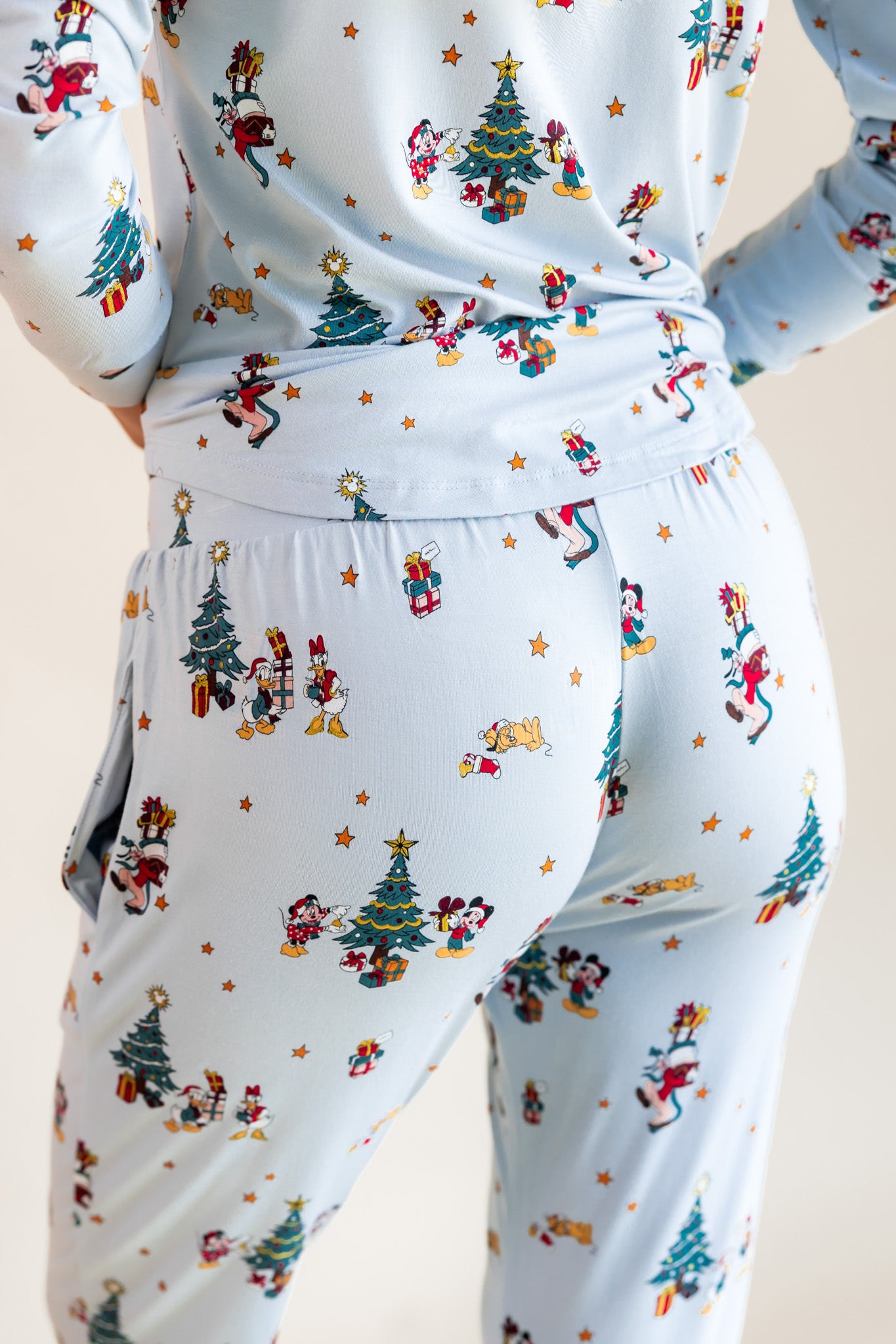 Back side of modal wearing Women's Jogger Pajama Set in Mickey & Friends Christmas print on a beige background