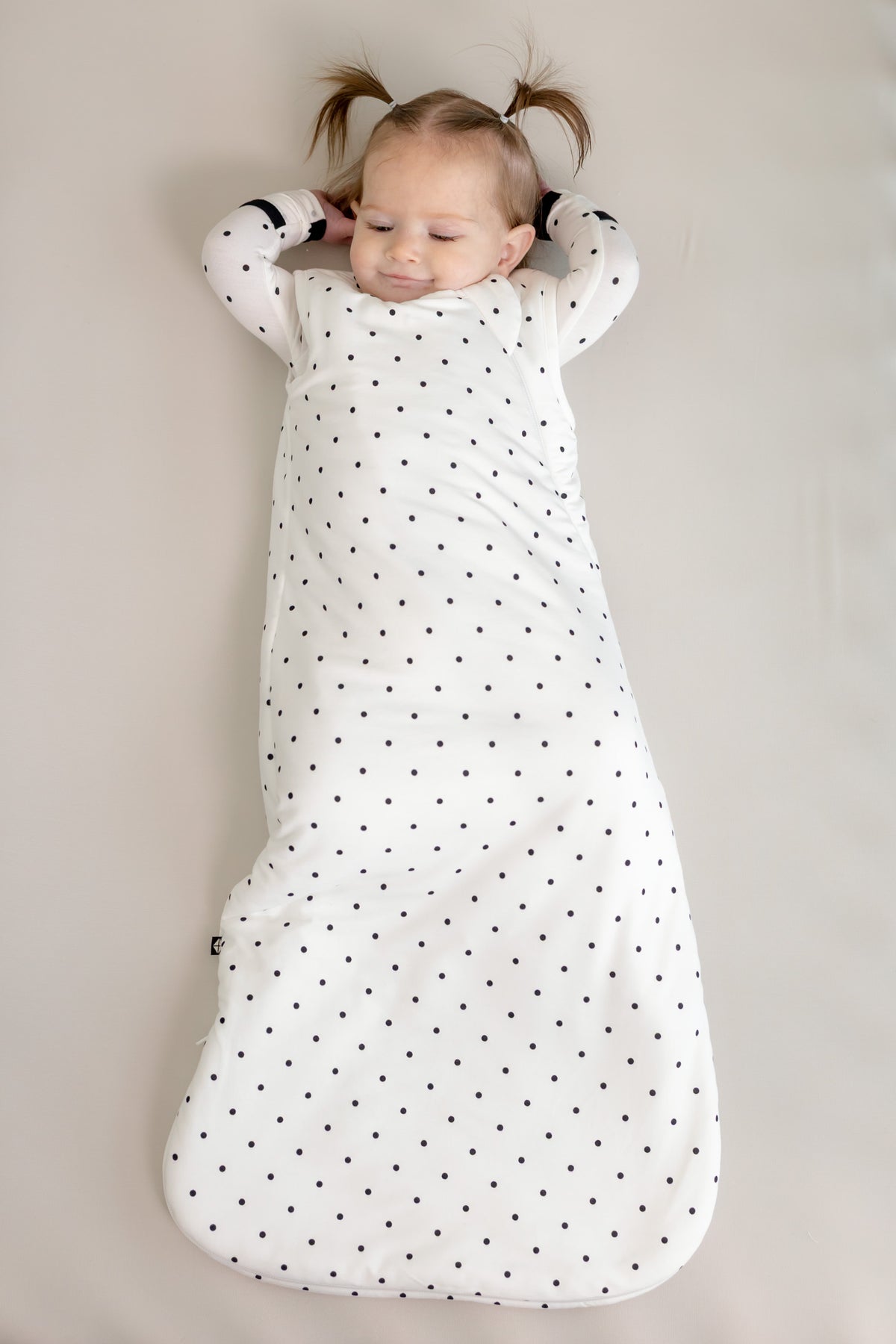 Baby wearing Sleep bag in Midnight Polka Dot print on a beige background