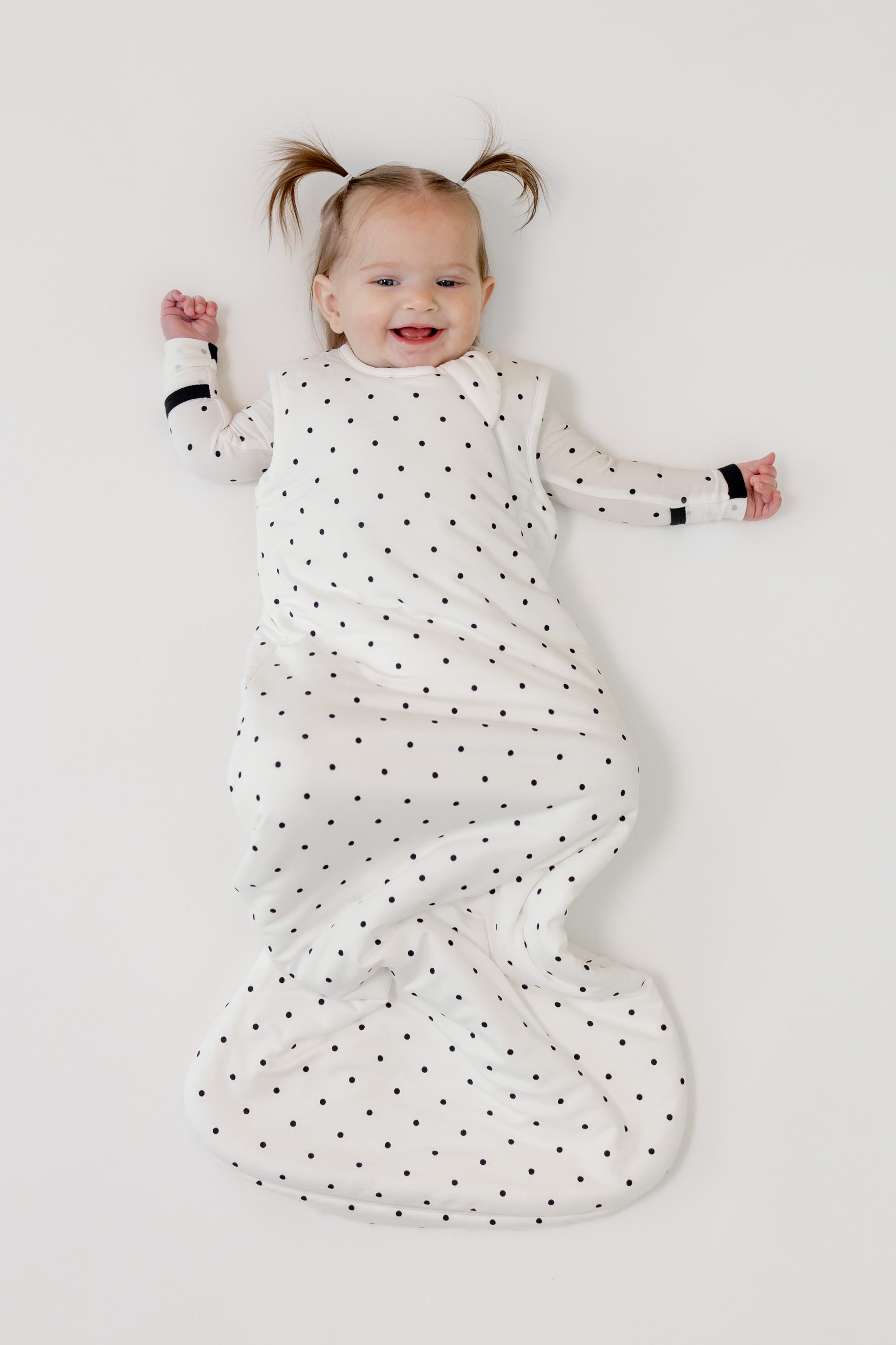Baby smiling in Sleep bag with Midnight Polka Dot print on a white background