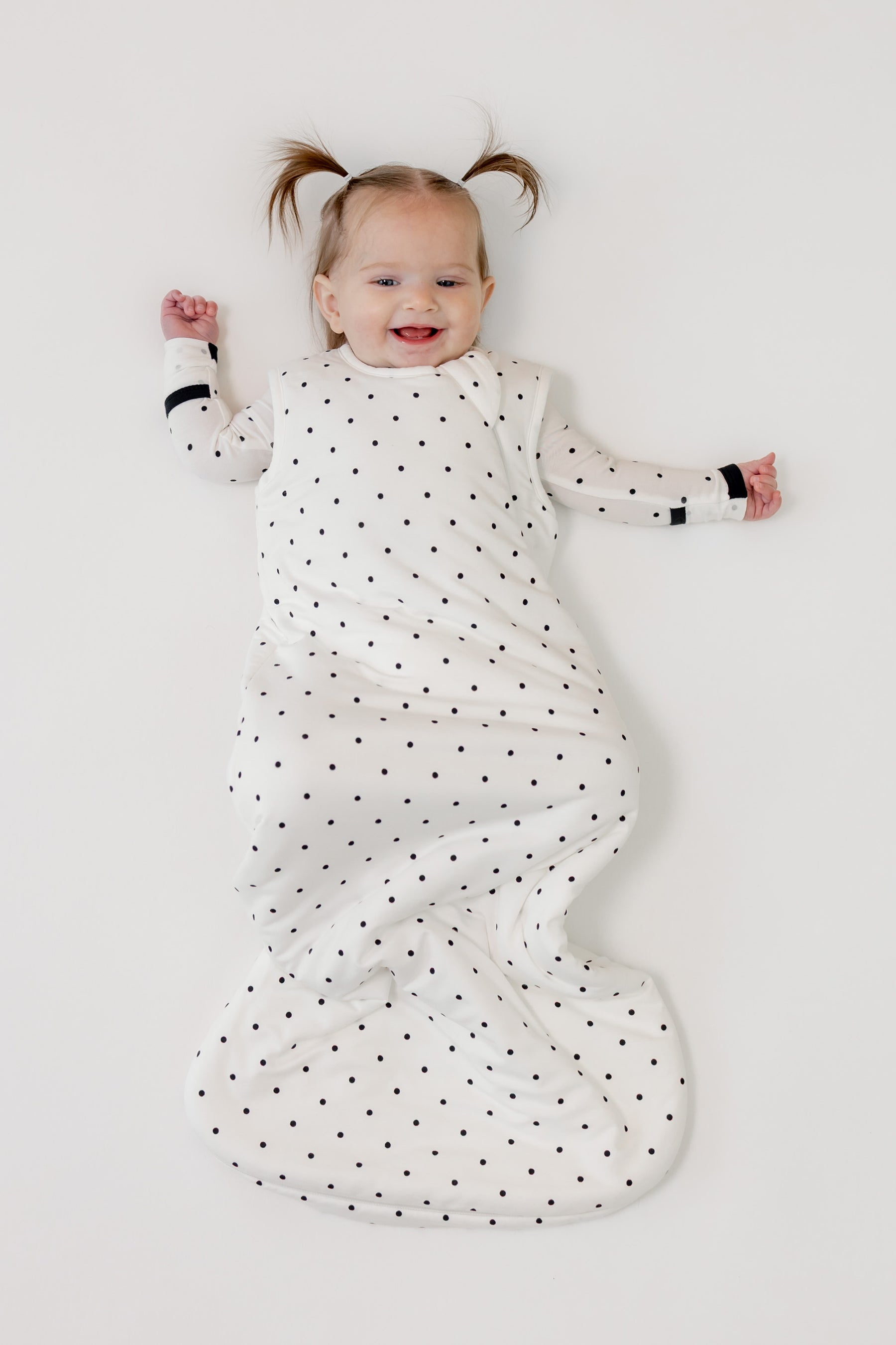 Baby smiling in Sleep bag with Midnight Polka Dot print on a white background