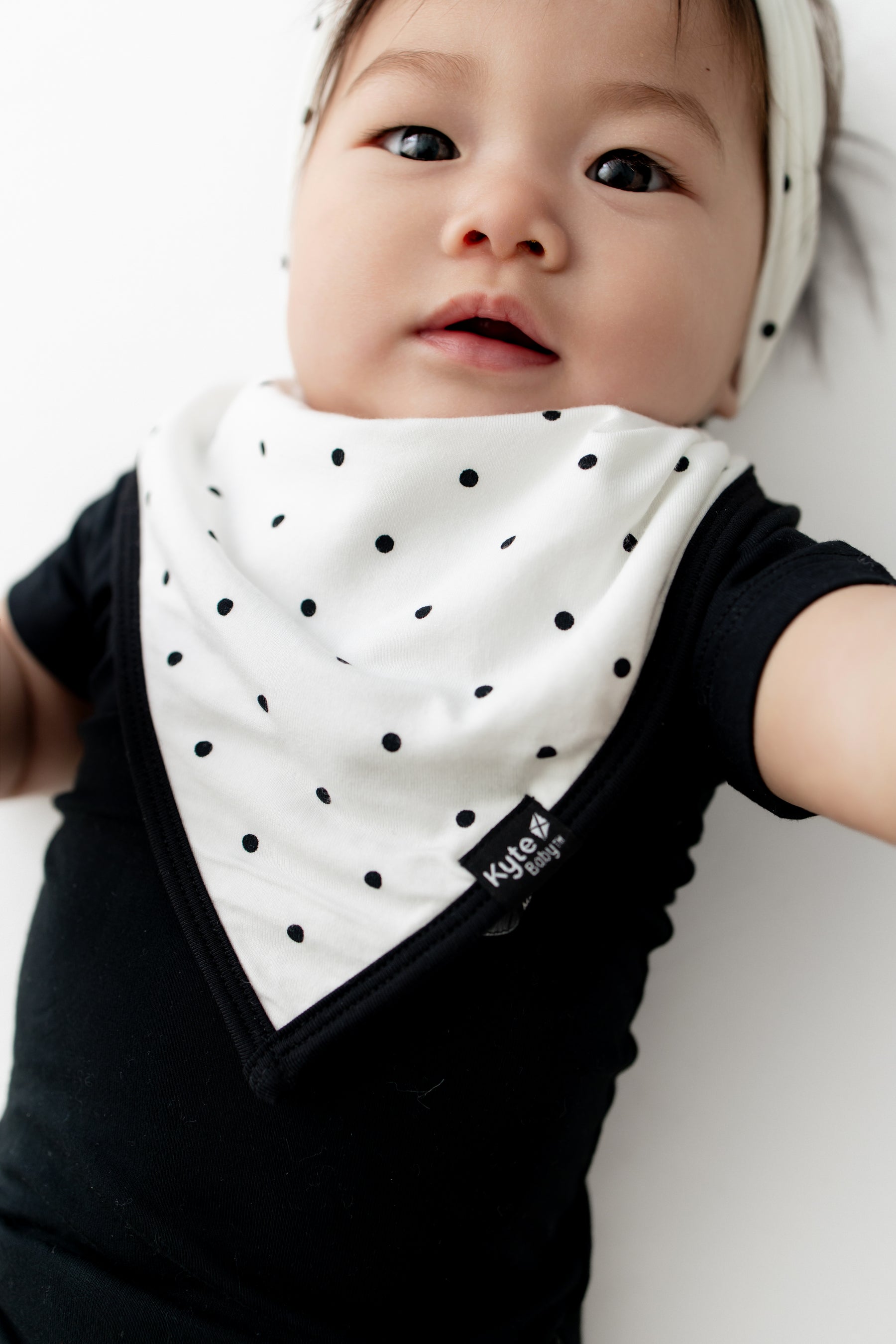 Baby wearing Midnight Polka Dot print Bib over a black bodysuit on a white background