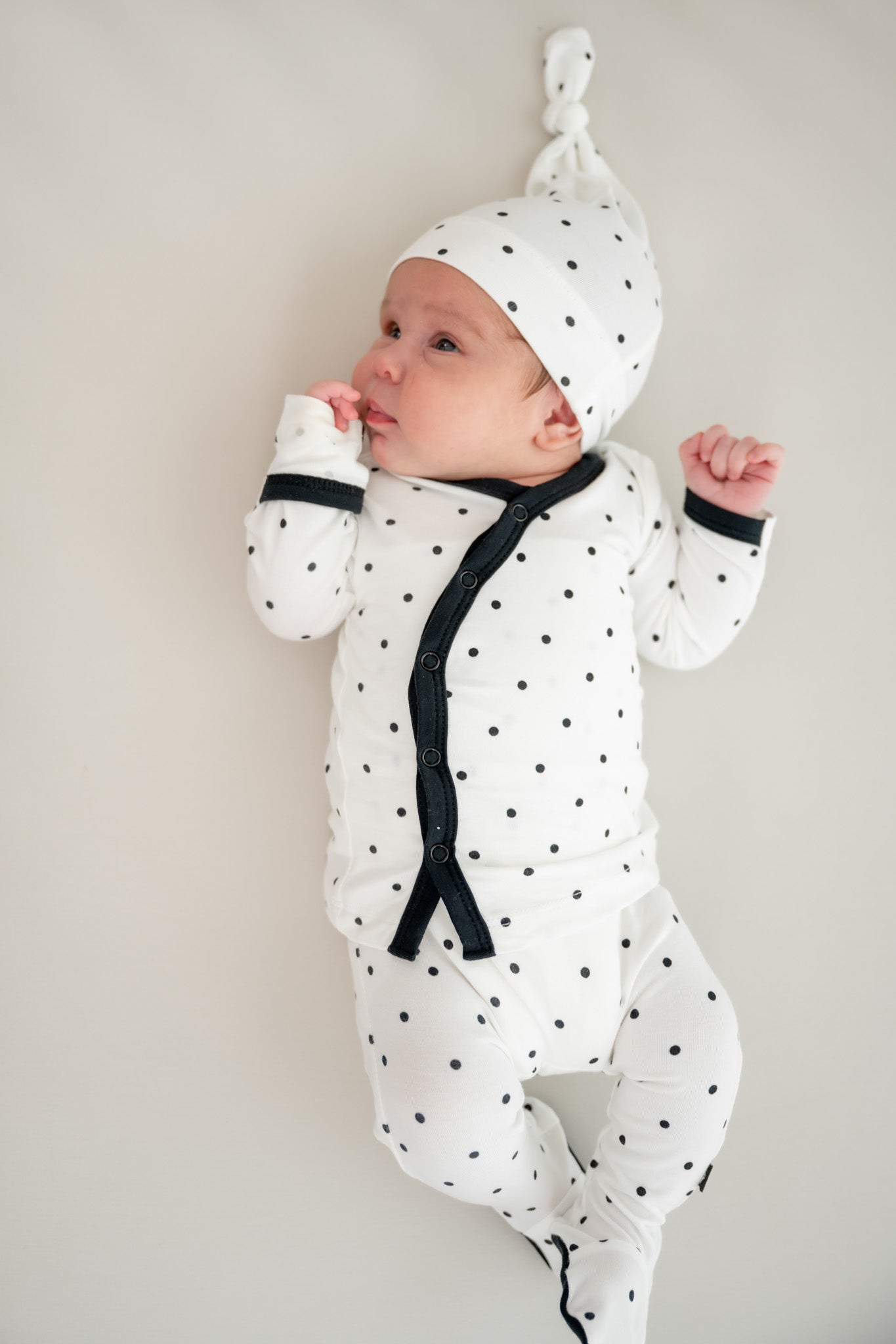 Baby wearing take me home set with cap in Midnight Polka Dot print on a beige background