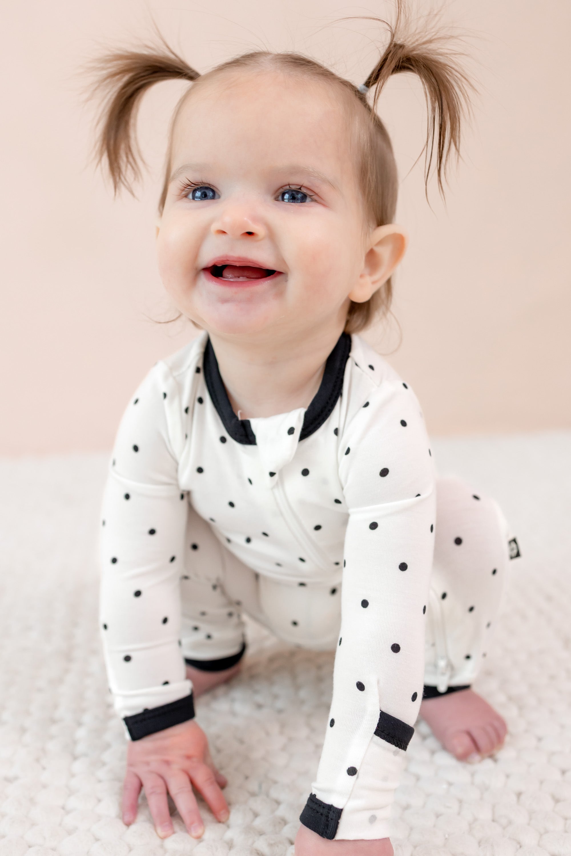 Child wearing midnight polka dot print zippered romper on beige background