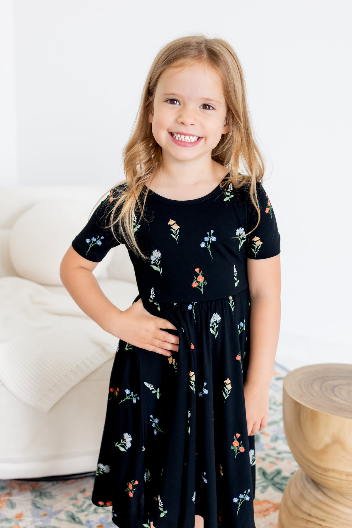 Girl smiling in Twirl Dress in Midnight Wildflower print standing in a living room