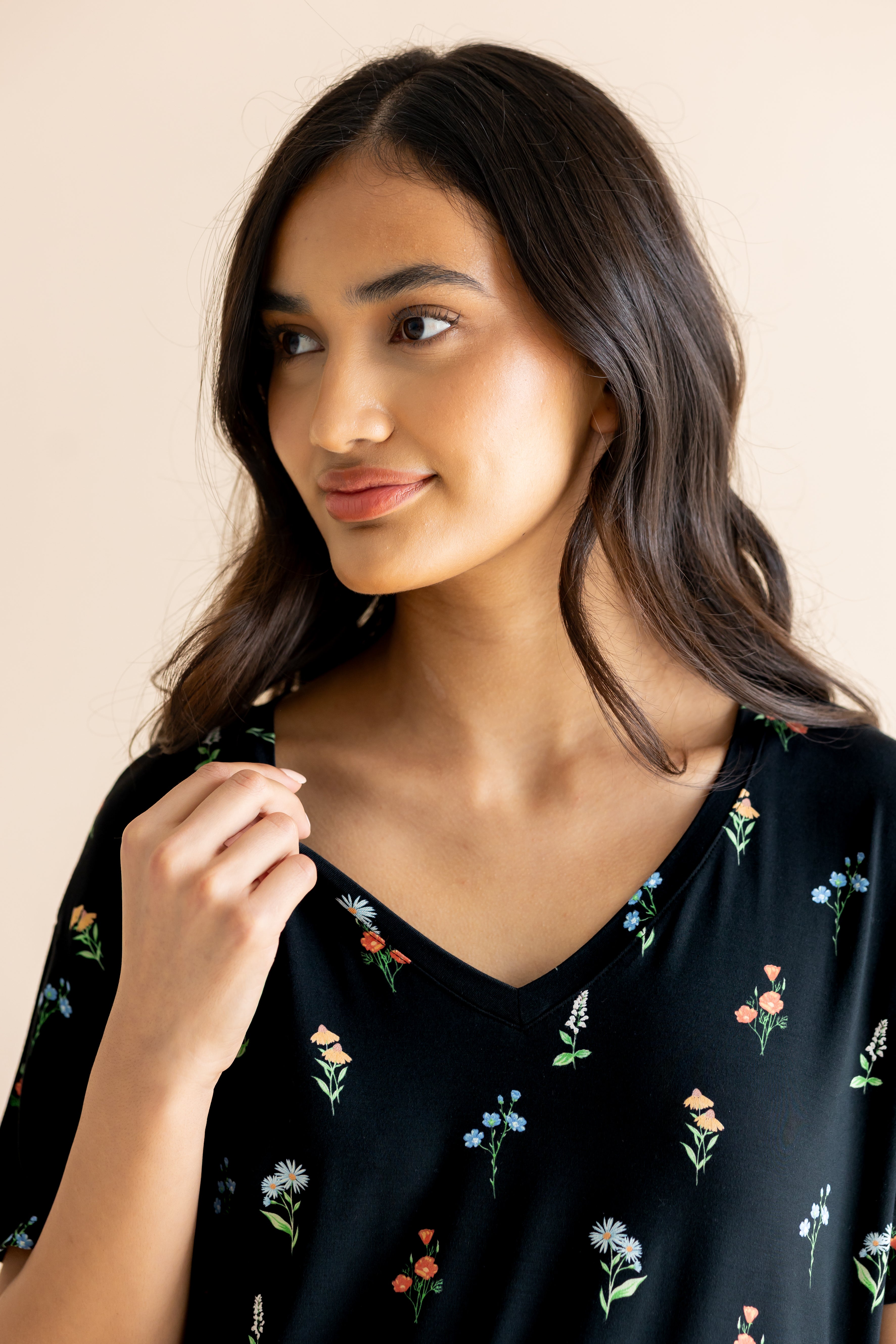 Model smiling in Women's Relaxed Fit V-Neck in Midnight Wildflower print on a beige background
