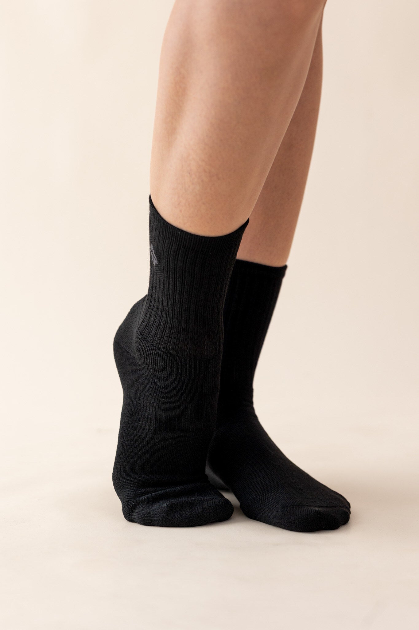 The Adult Crew Socks in Midnight on the feet of a model showing the soft and stretchy fabric of the material