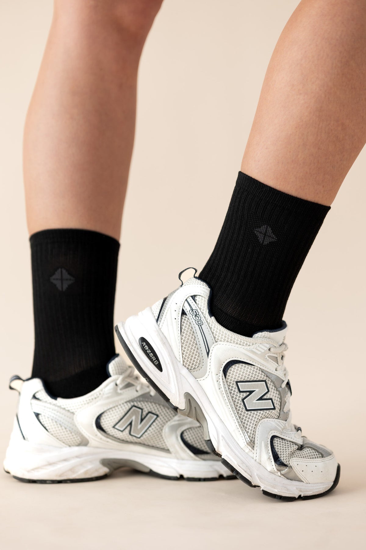 Model wearing the Adult Crew Socks in Midnight with the kyte logo visible wearing black and white running shoes