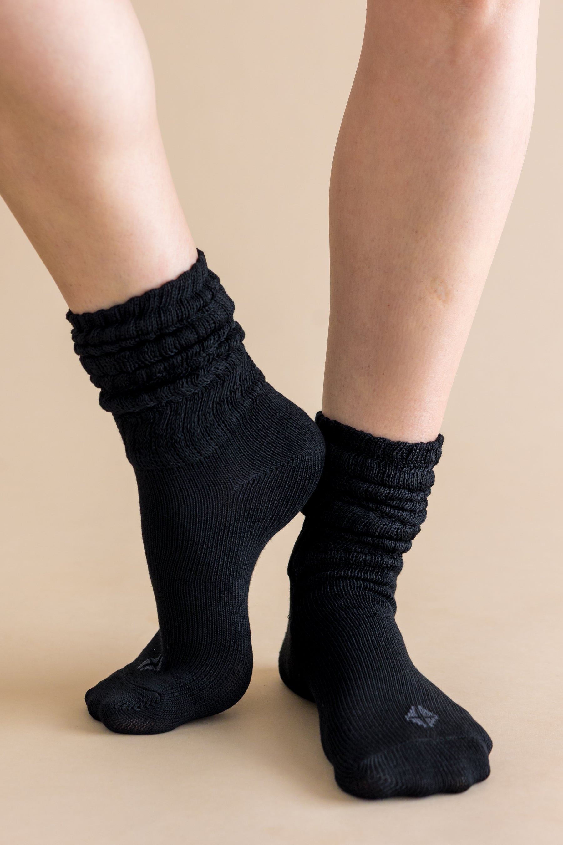Adult Scrunch Socks in Midnight shown on a models feet with the Kyte Baby logo visible