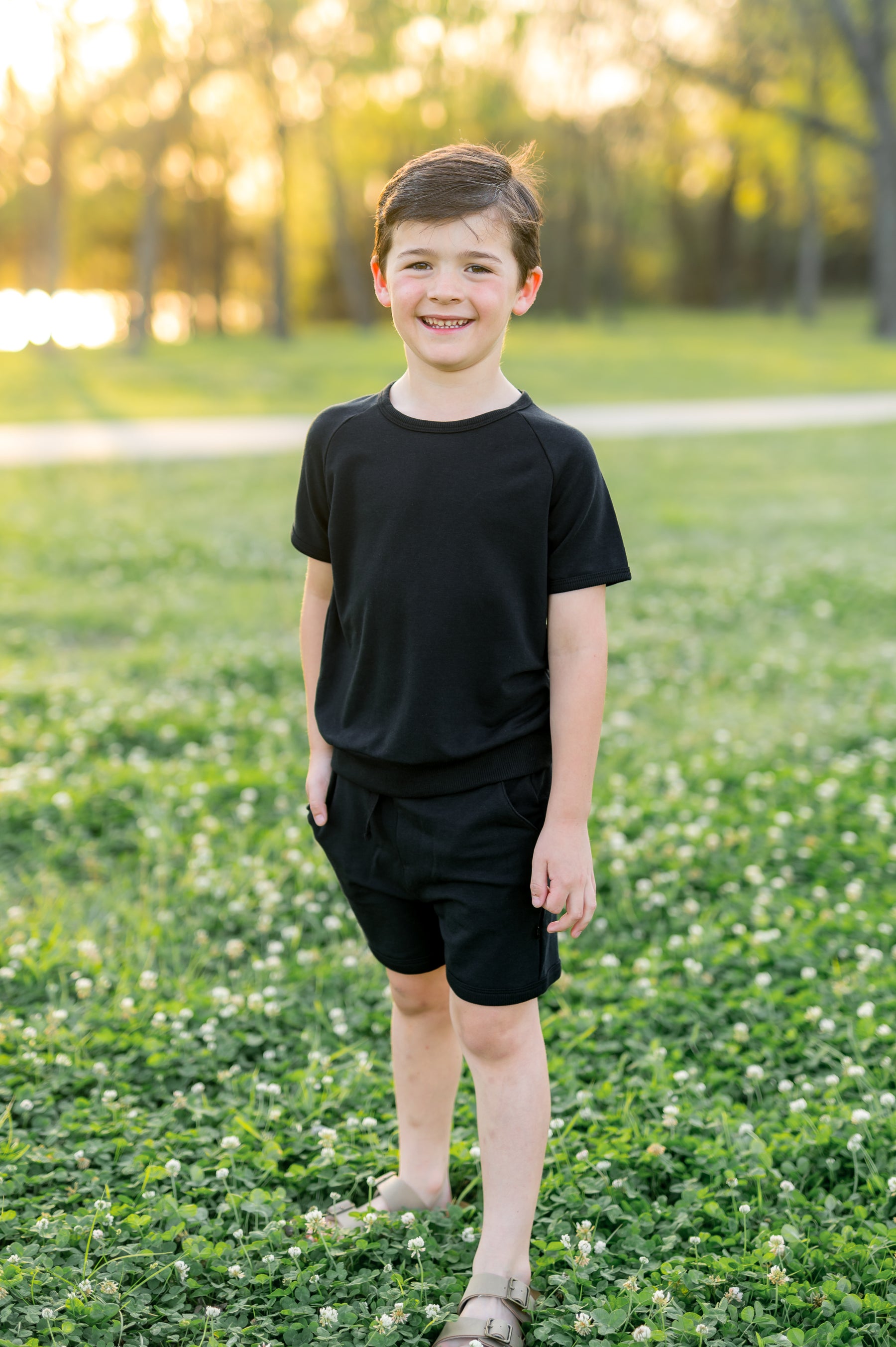 Young boy posing in a grass field wearing the Short Sleeve Jogger Set in Midnight