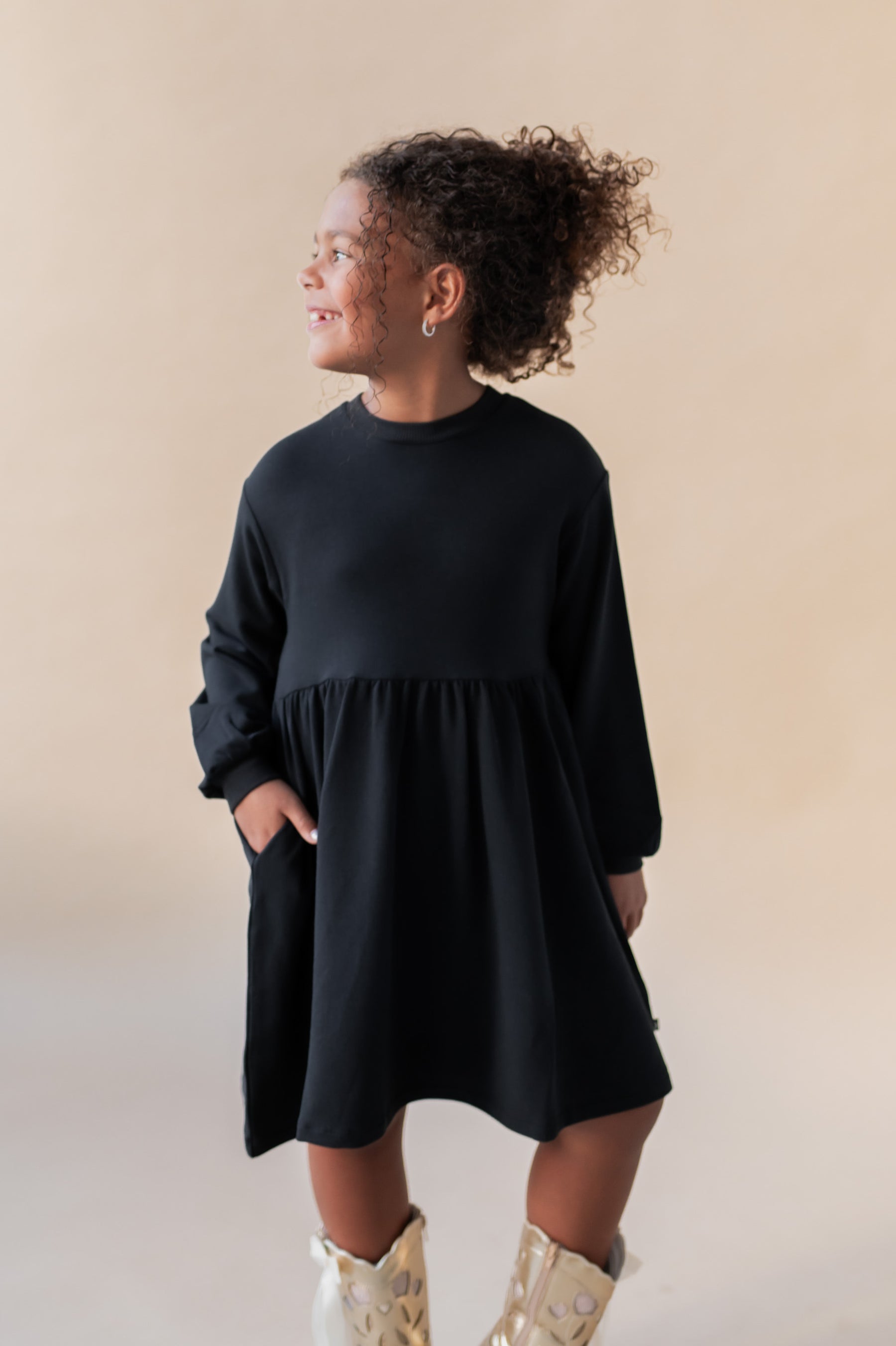 Girl posing in Long Sleeve Skater Dress in Midnight color on a beige background