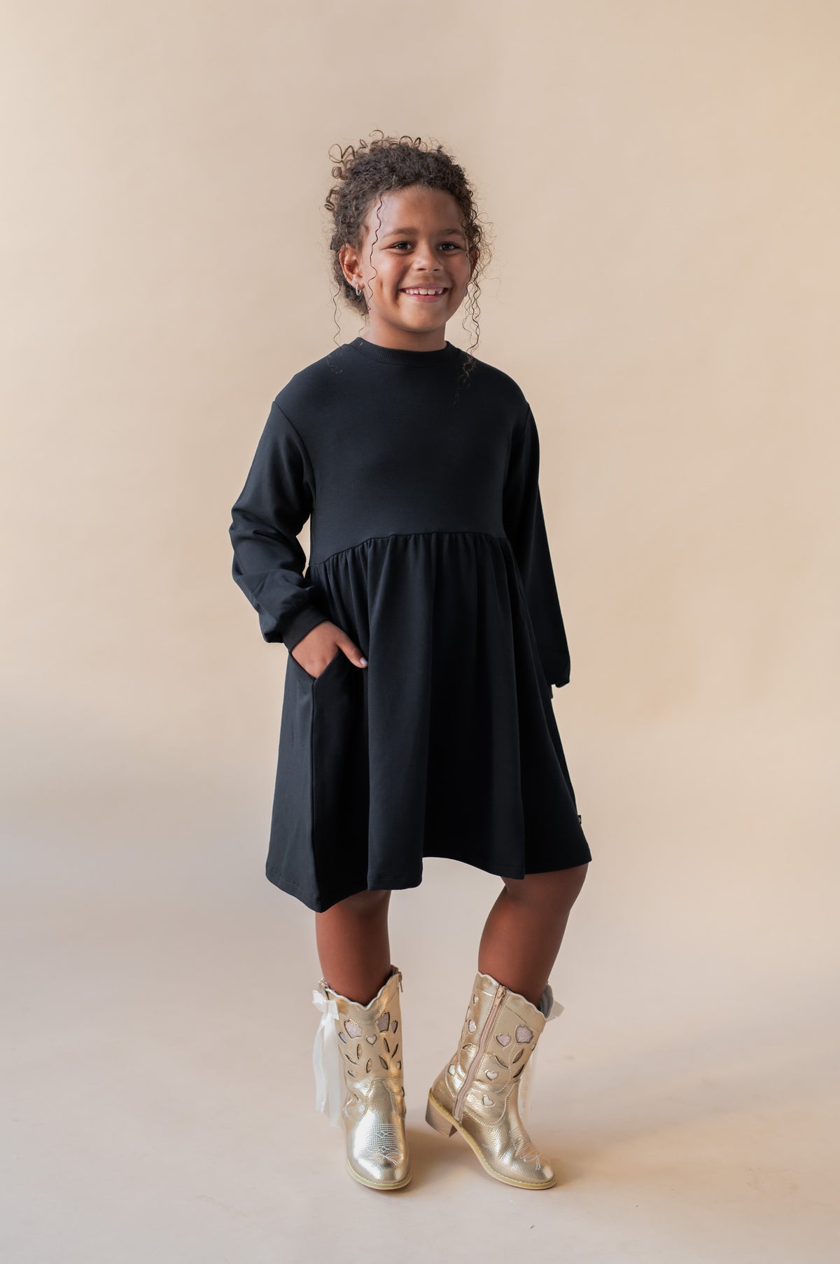 Girl smiling in Long Sleeve Skater Dress in Midnight color on a beige background