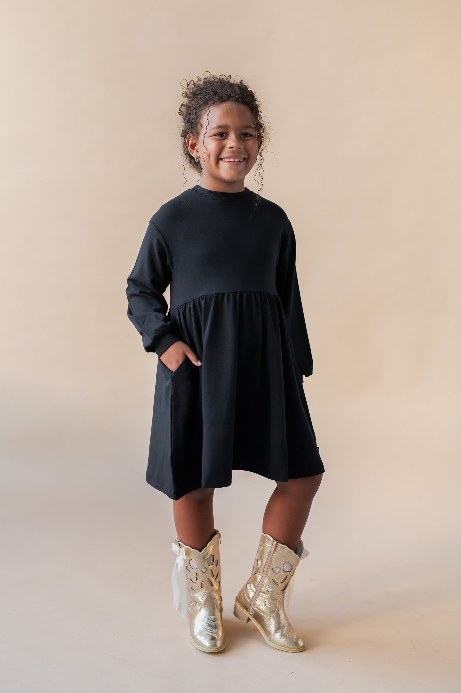 Girl smiling in Long Sleeve Skater Dress in Midnight color on a beige background