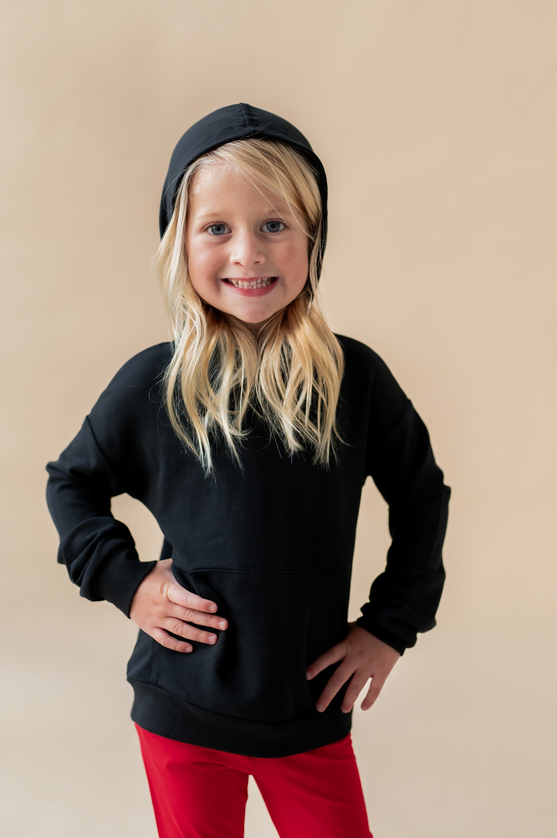 Girl wearing Hoodie in Midnight color over red pants on a beige background