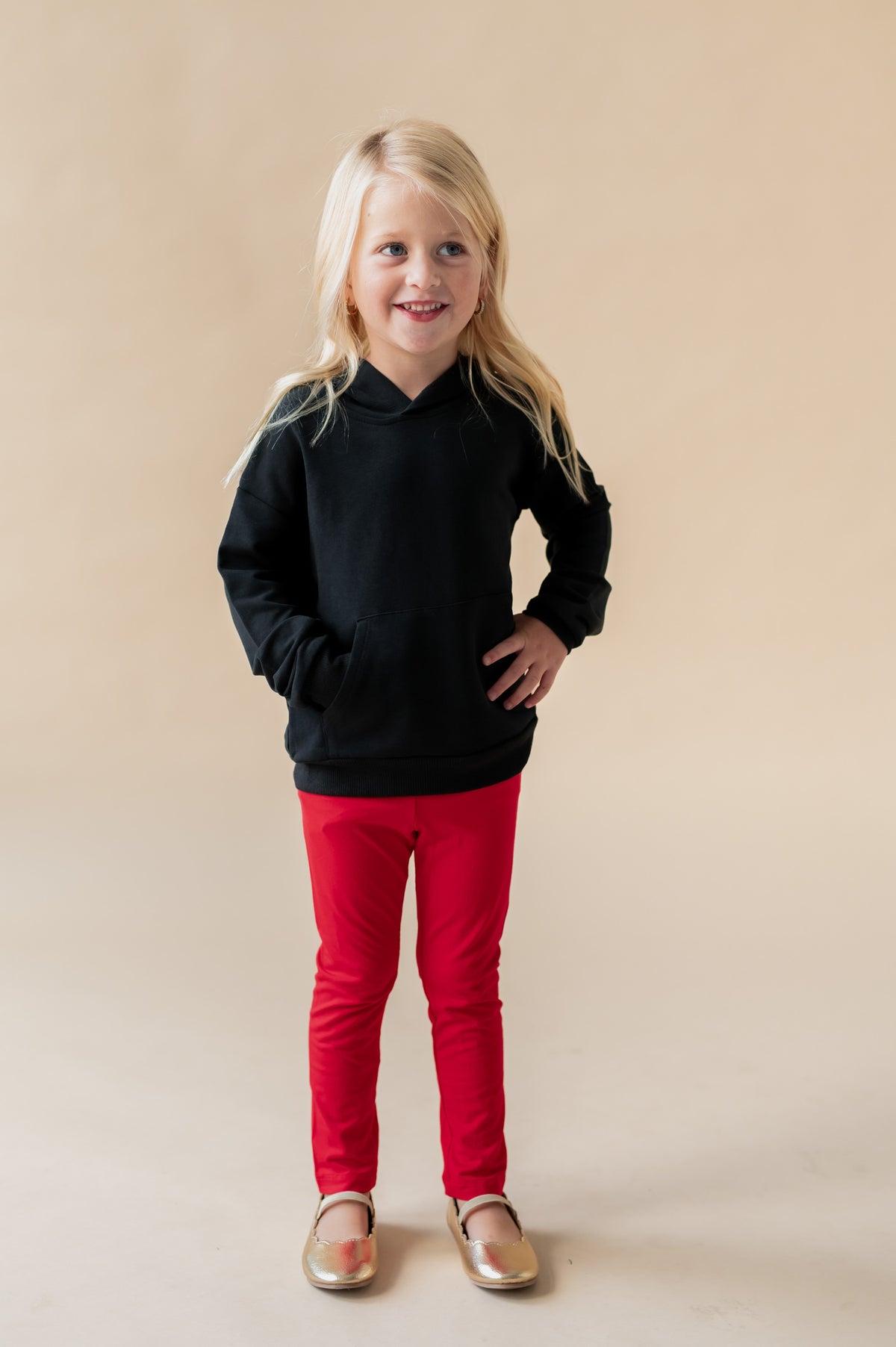 Girl posing in Hoodie in Midnight color over red pants on a beige background