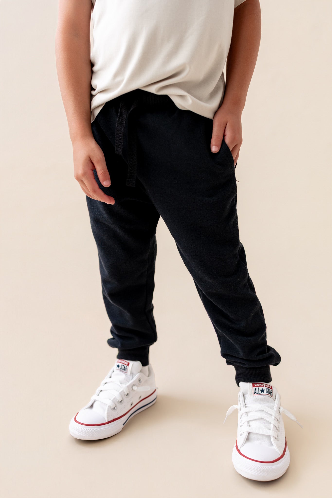 Modal wearing Jogger Pant in Midnight color under white T-shirt and shoes on a beige background