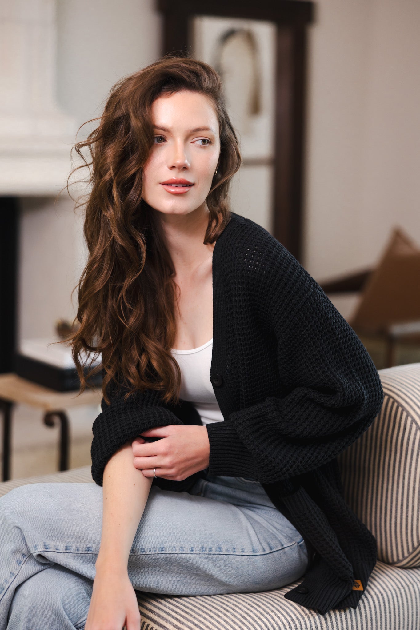 Modal posing in Chunky Knit Women's Waffle Cardigan in Midnight over white camisole and blue jeans