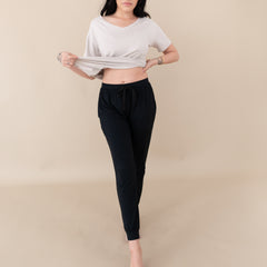 Woman modeling Women's Jogger Pants in Midnight with an oat v-neck with legs slightly crossed
