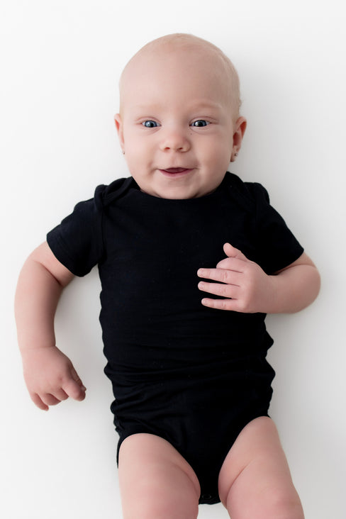 Baby wearing a black onesie on a white background