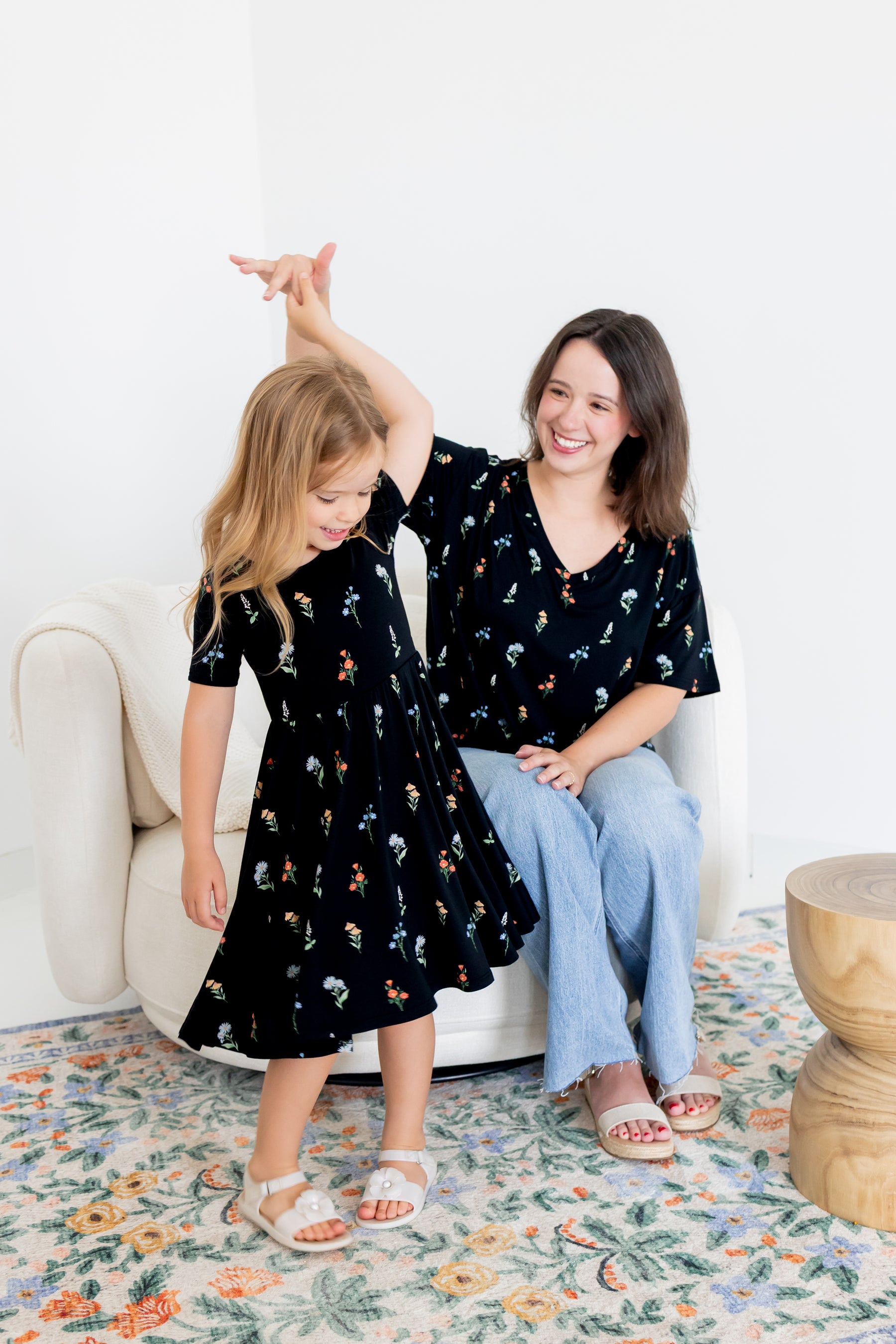 Girl twirling in Twirl Dress in Midnight Wildflower print with a model wearing Women's Relaxed Fit V-Neck in similar print over blue jeans