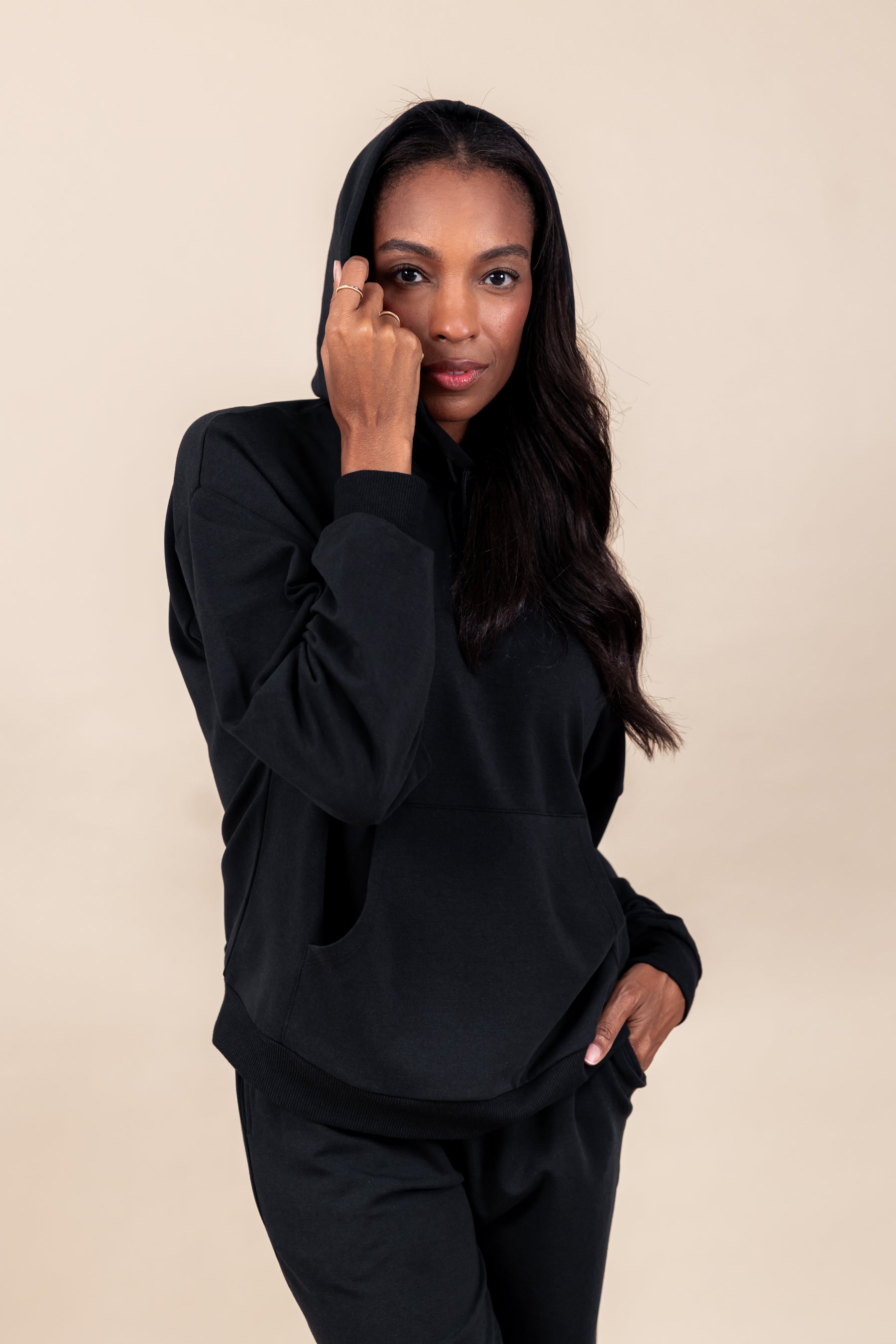 Woman posing in Women's Hoodie in Midnight color over similar color women's jogger pants on a beige background
