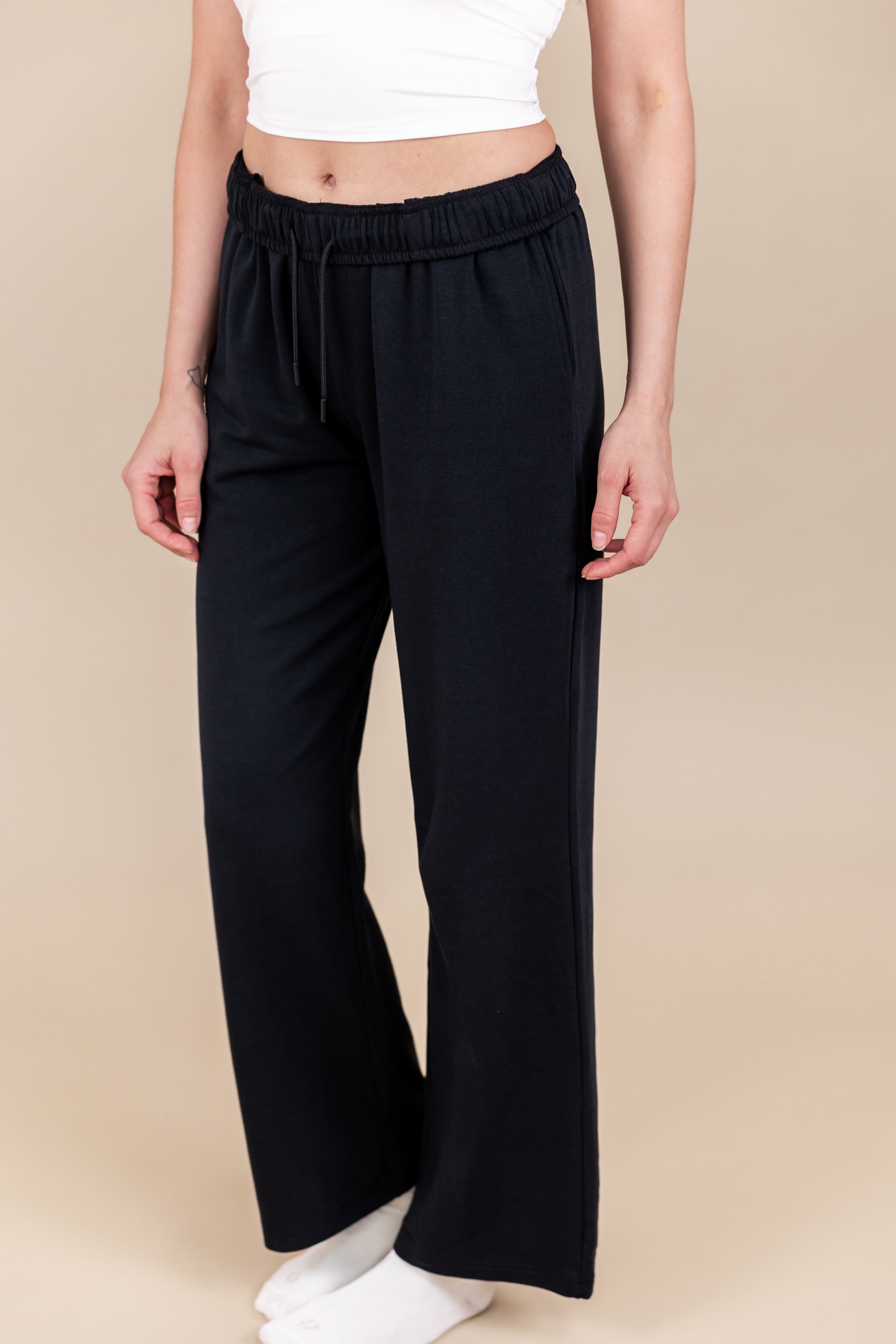 Modal wearing Women's Sweatpants in Midnight color under white flex bra tank and white socks on a beige background